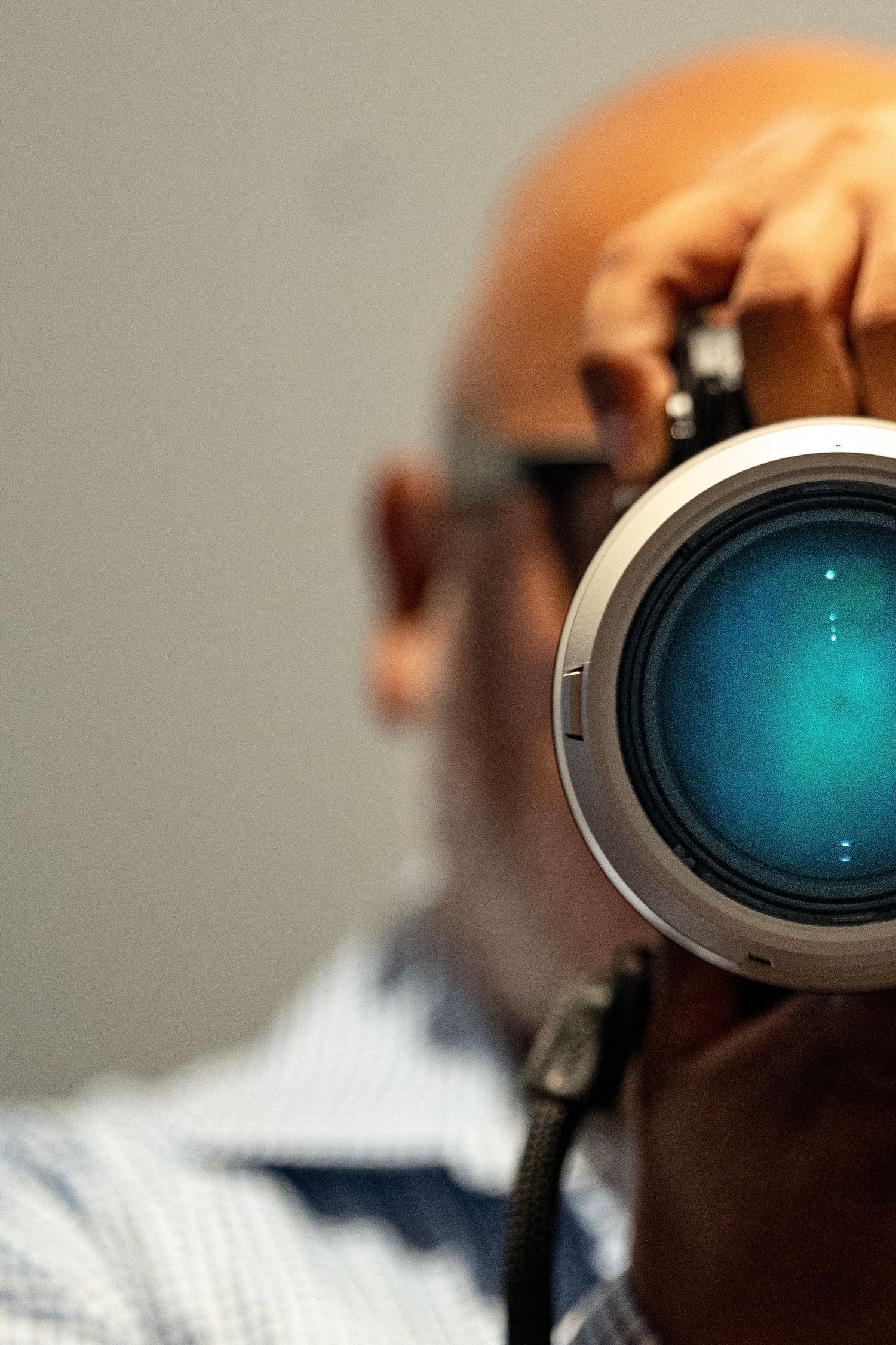 Professional camera lens with blue reflection photographed against neutral background.