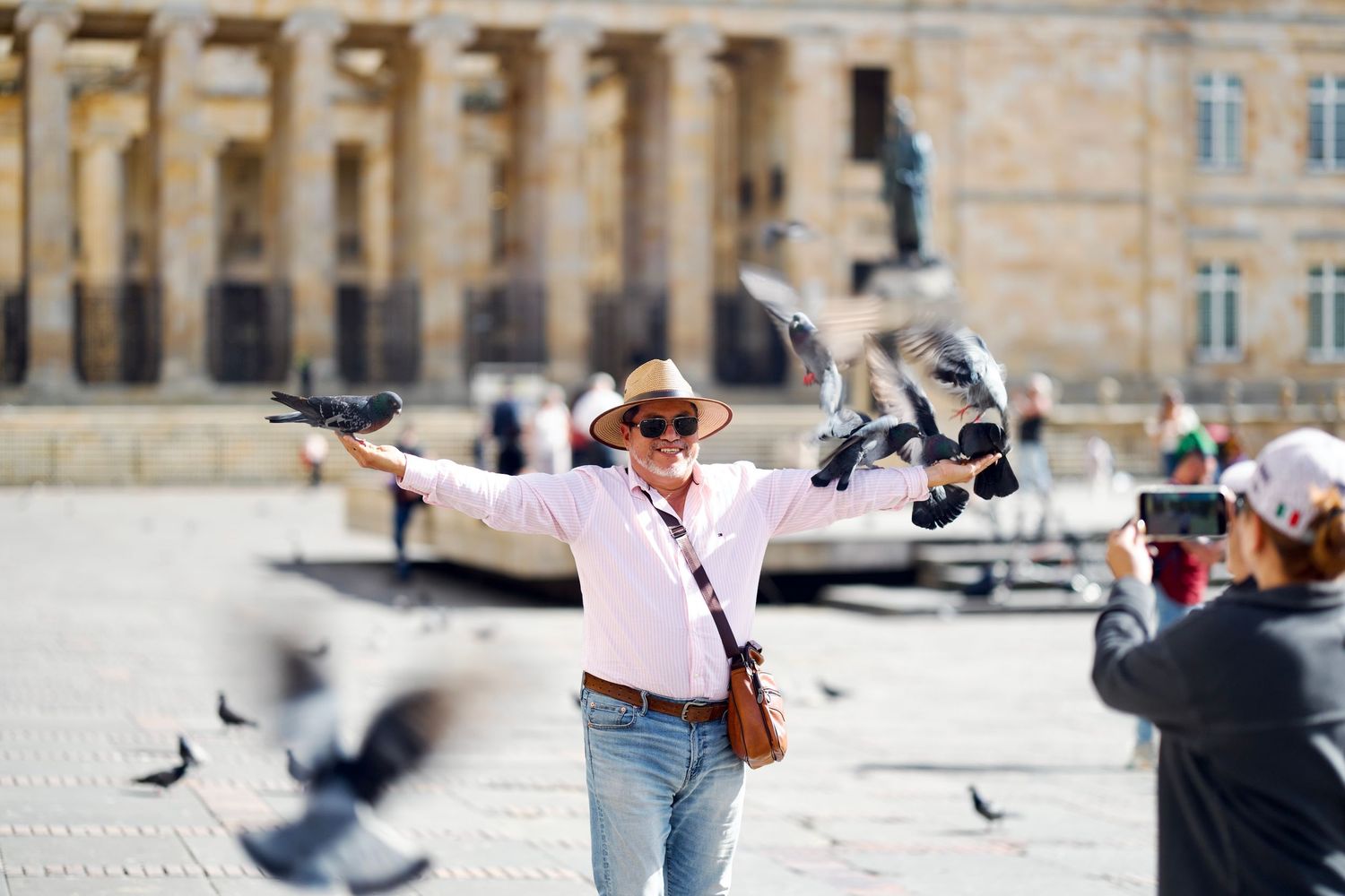 People feeding and interacting with pigeons in a public square.