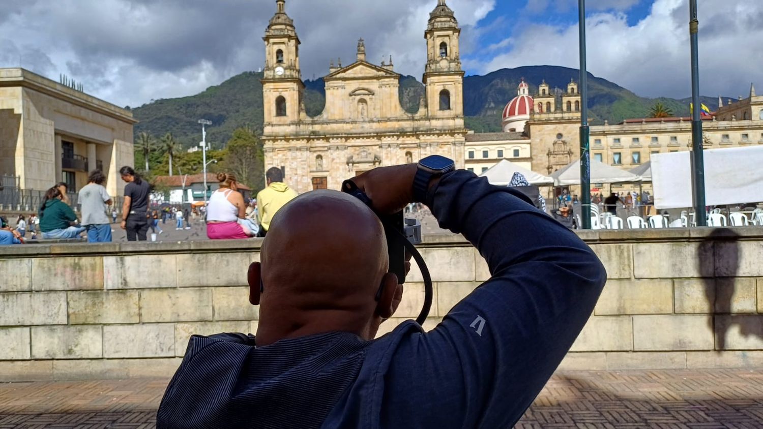 Historic church buildings and mountains under dramatic cloudy sky in Latin America.