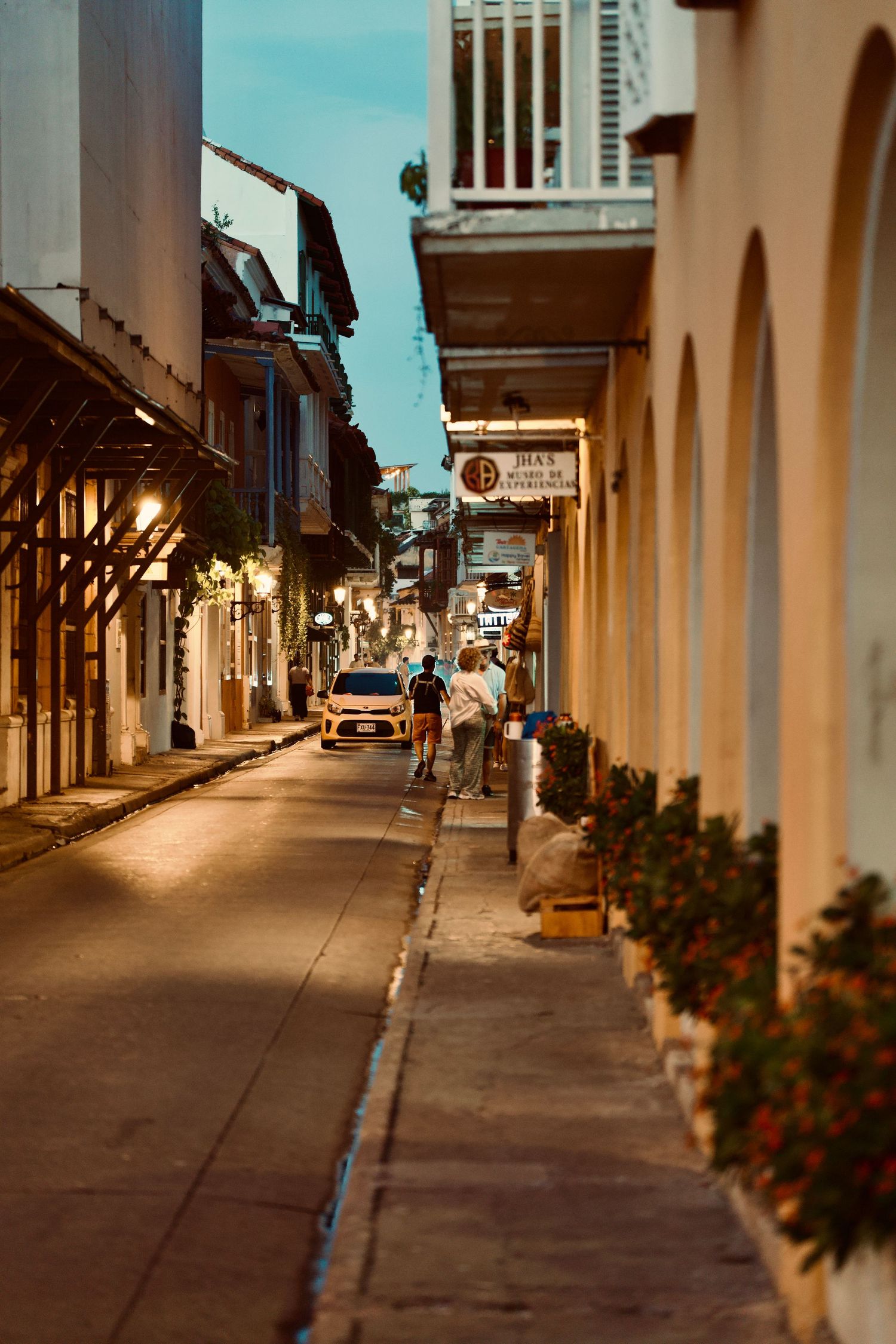 Quiet colonial street with white columns and peach-colored buildings at dusk.
