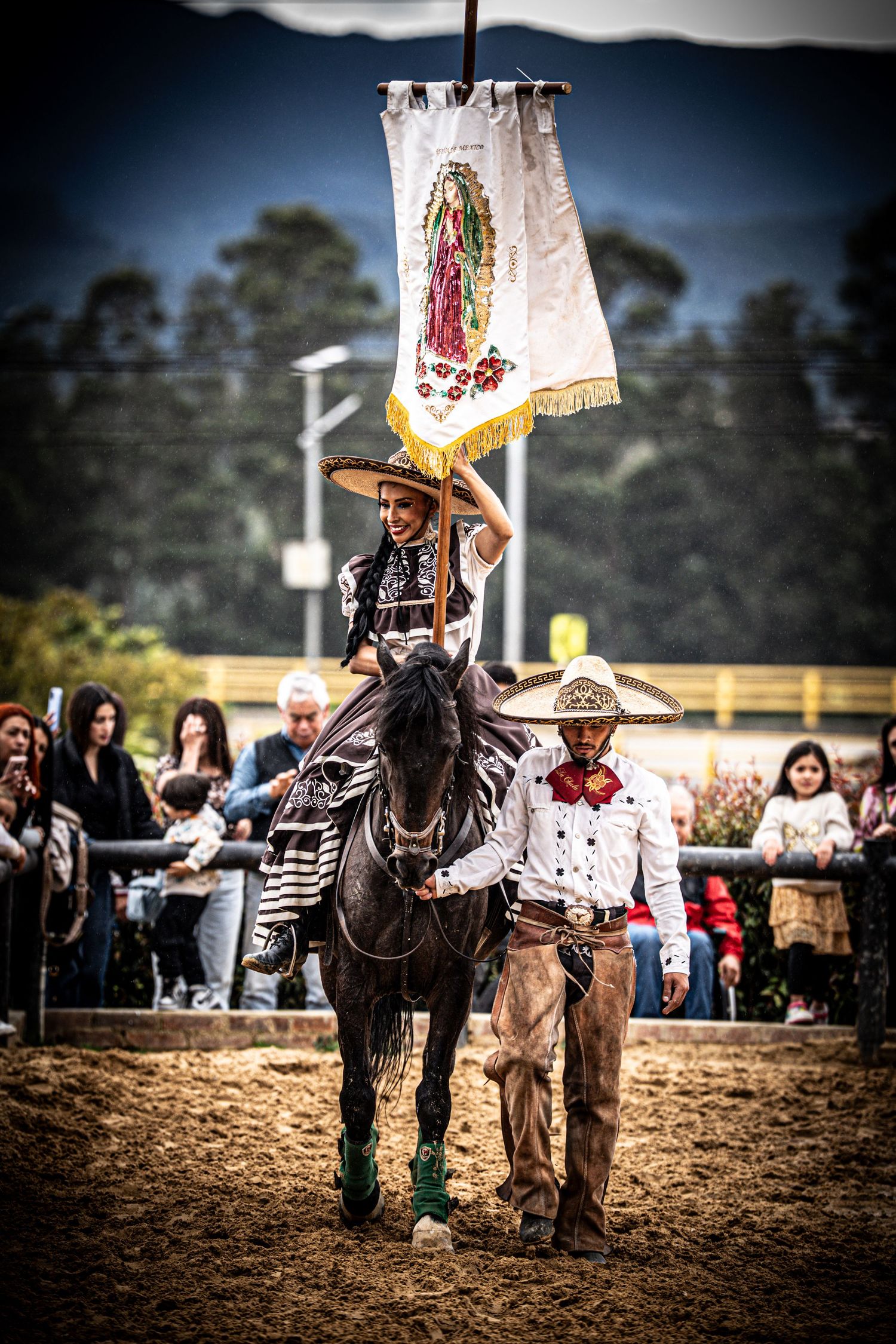 Charros carry flags while performing horseback demonstrations at a Mexican rodeo event.