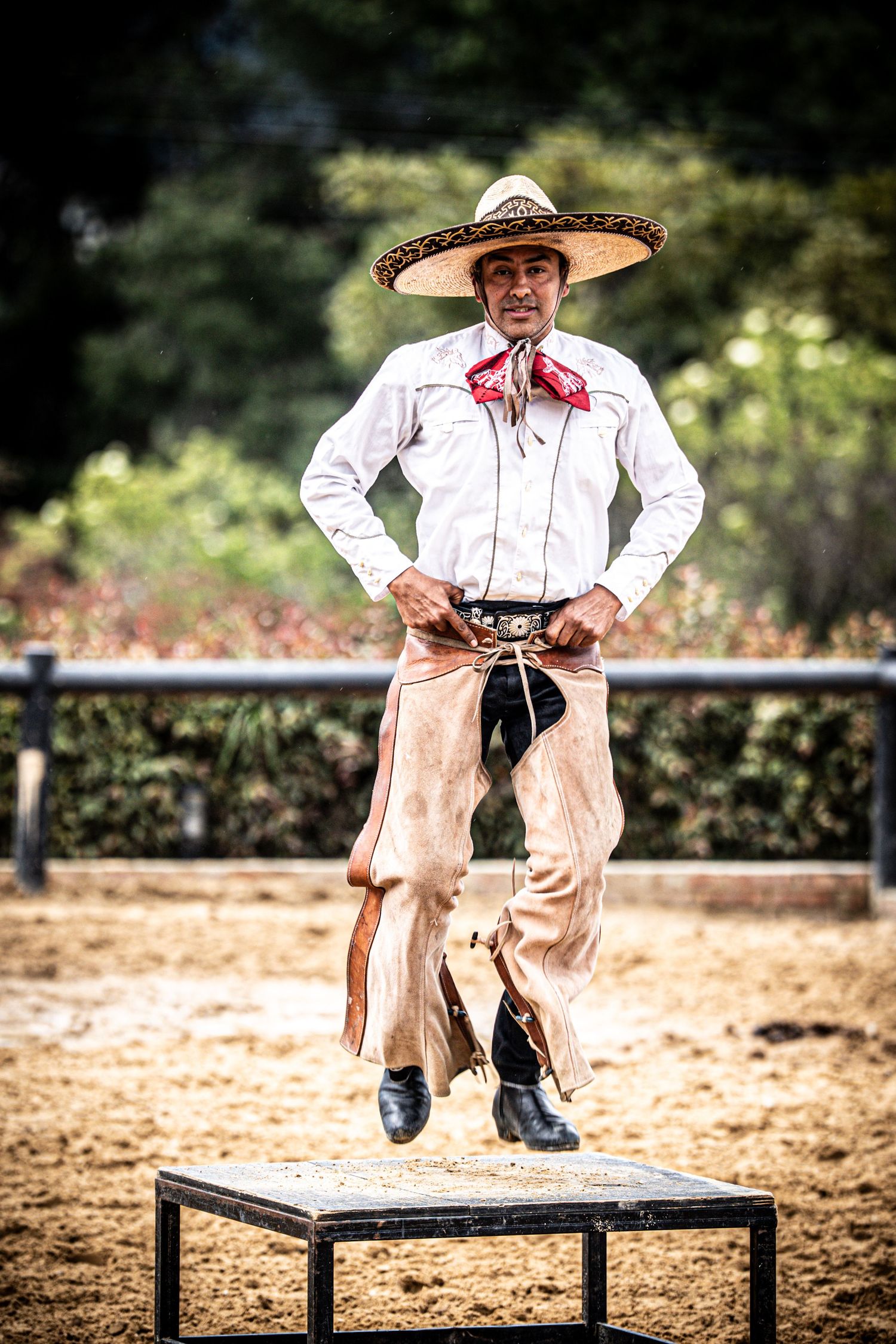 Traditional Mexican charro demonstrates acrobatic skills on wooden platforms in a rodeo arena.