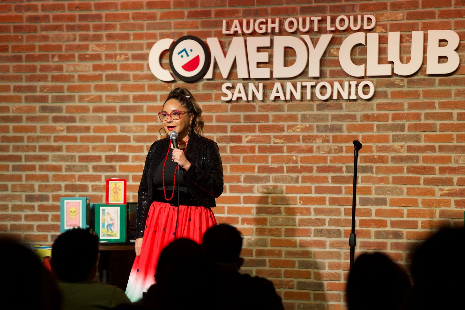 Stand-up comedy performance at San Antonio Comedy Club with illuminated signage.