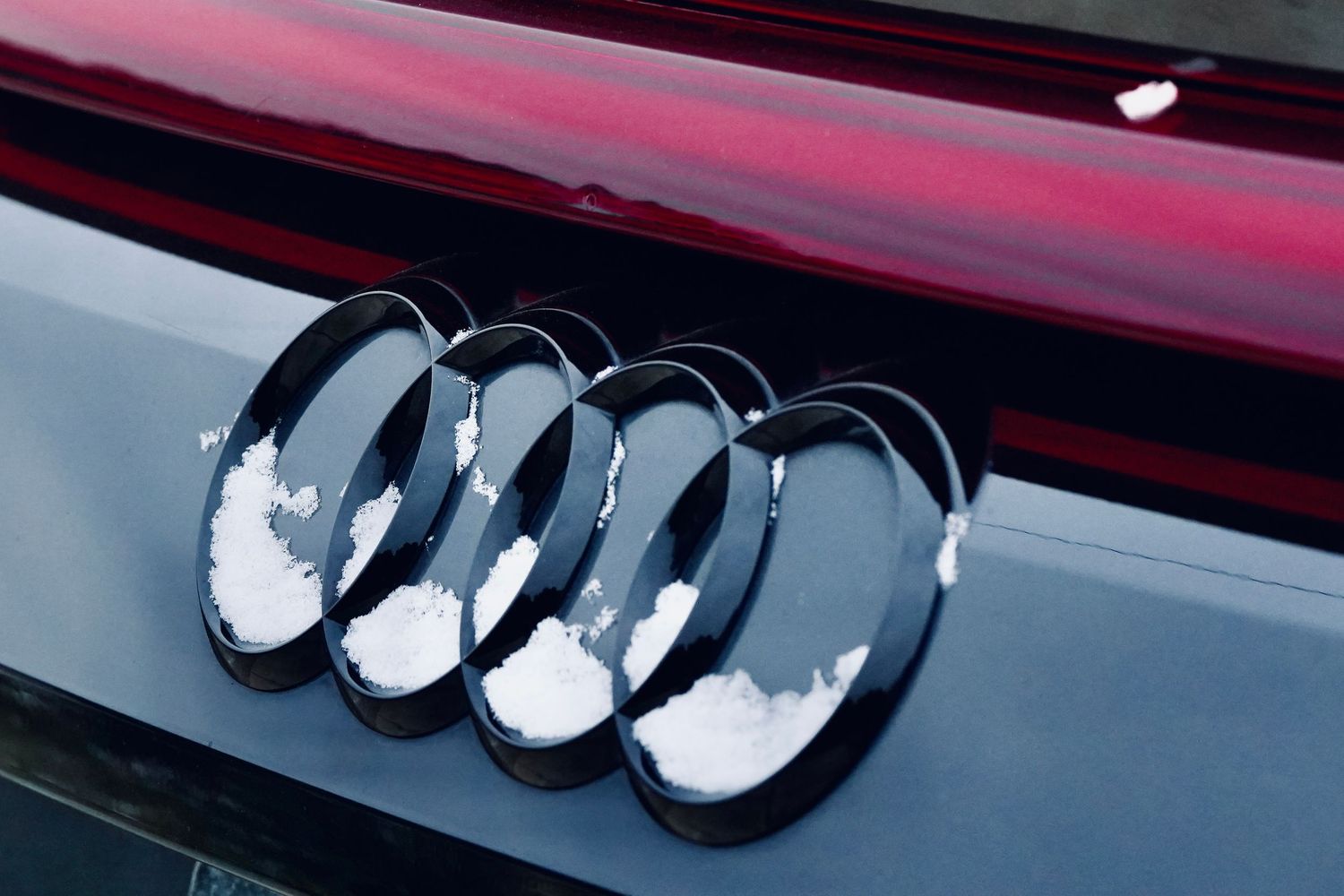 Chrome exhaust pipes mounted on glossy burgundy vehicle surface.