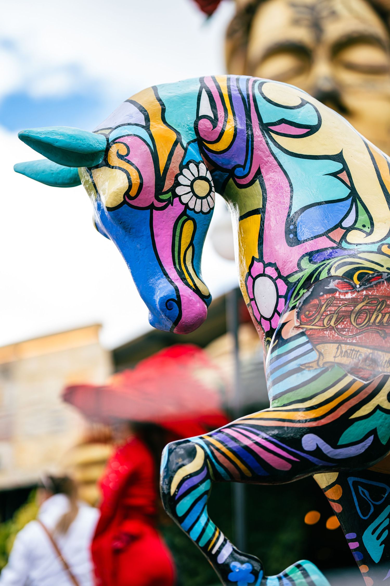 Colorful psychedelic art on a sculptural horse figure with swirling blue, pink and purple patterns.