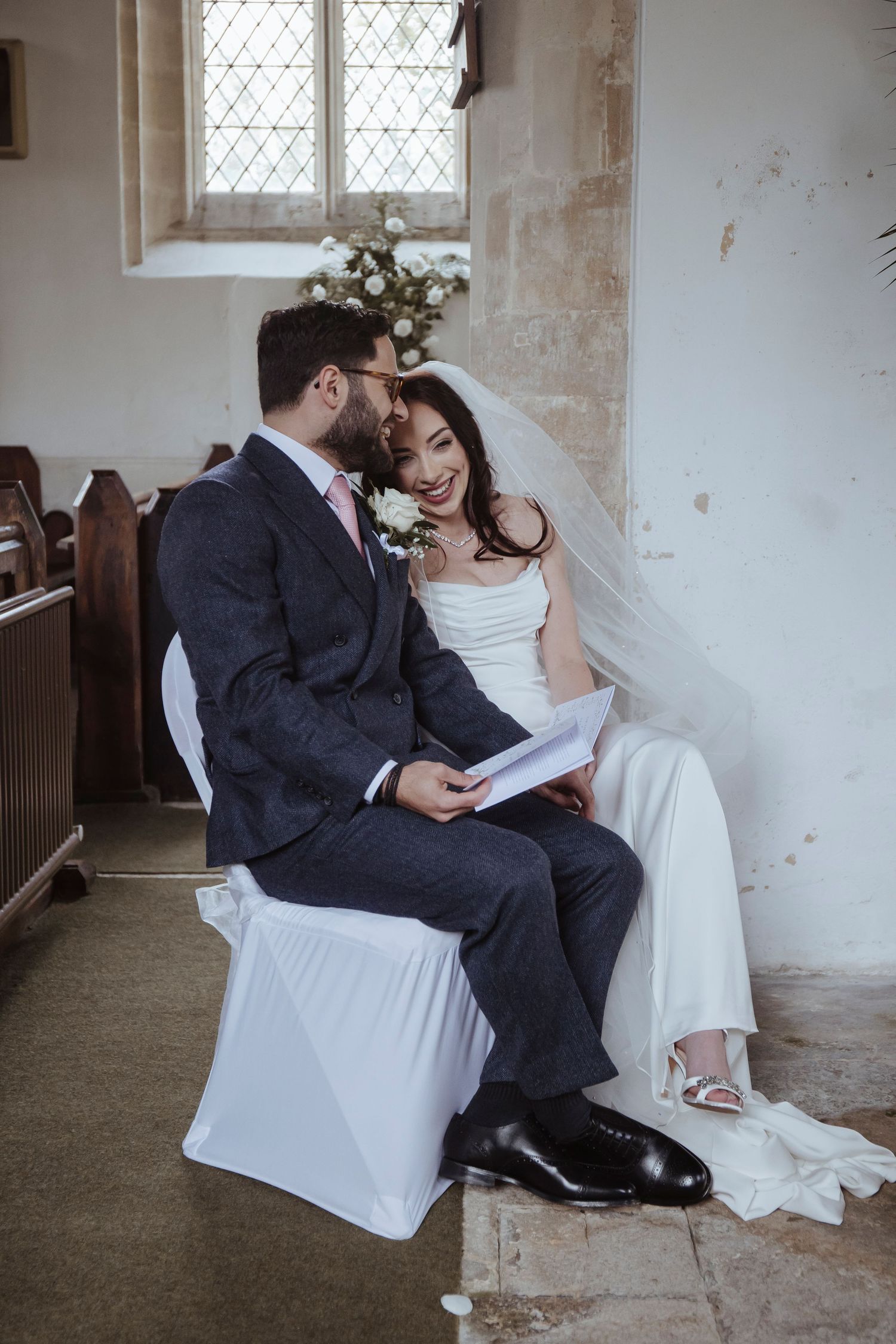 bride and groom smiling in each others arms whilst sat during the ceremony
