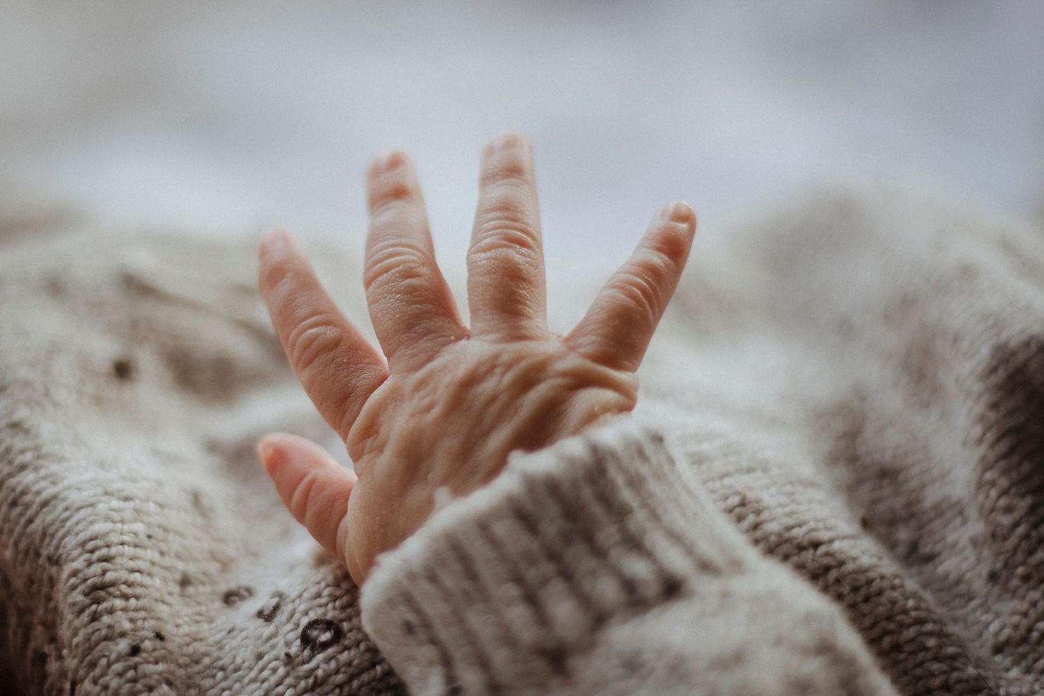 A tiny hand reaching out, wrapped in warmth and new beginnings.
