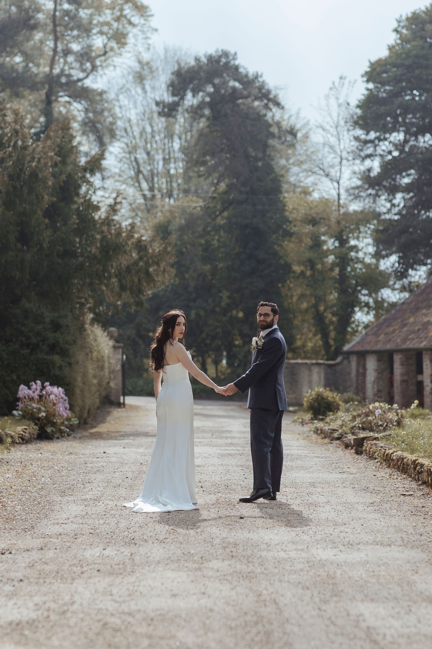 bride and groom staring back surrounded by beautiful nature