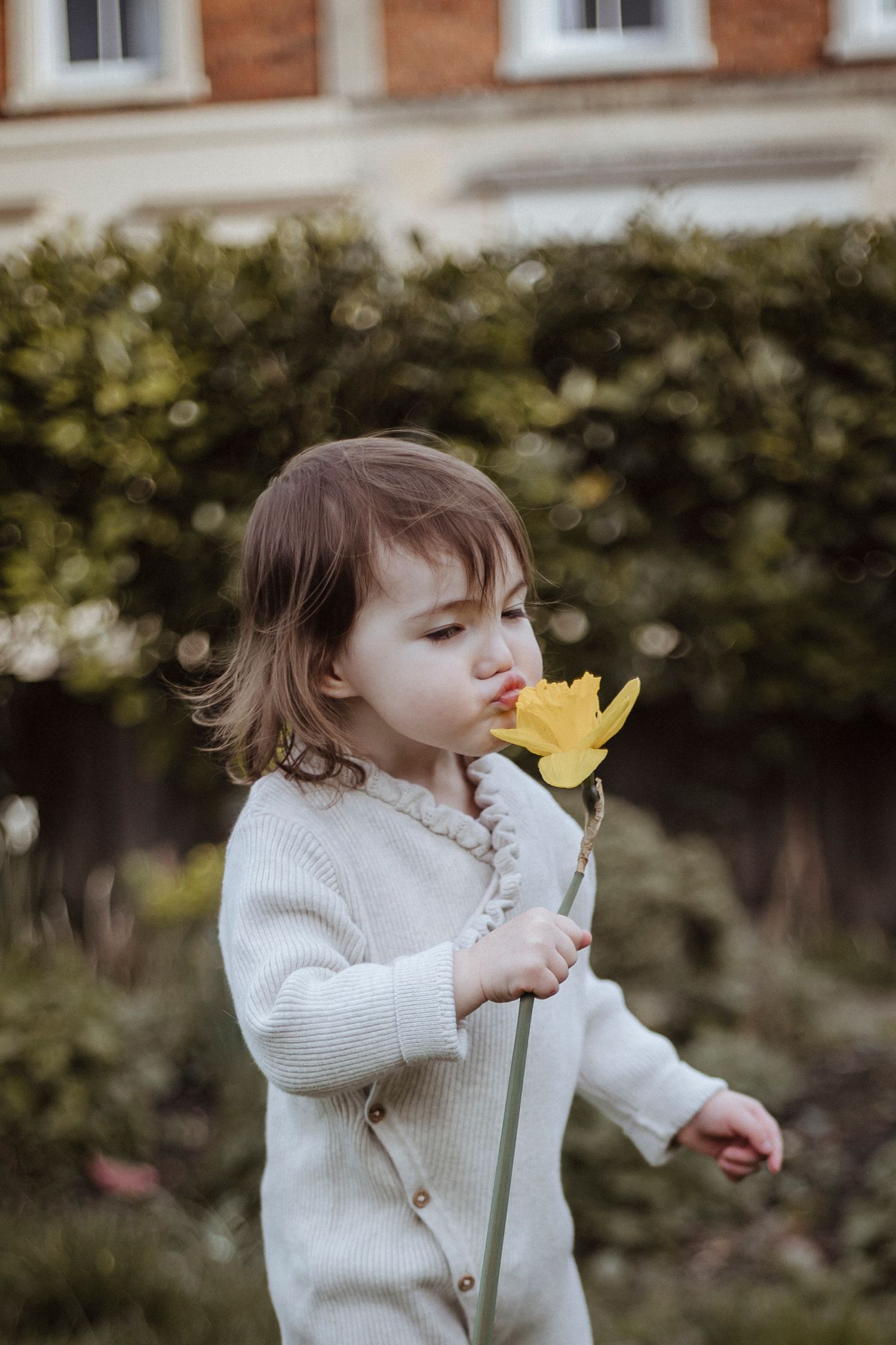 girl kissing and blowing on a yellow flower in the garden