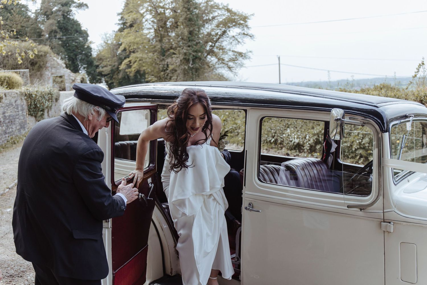 bride getting out of the wedding car in the countryside