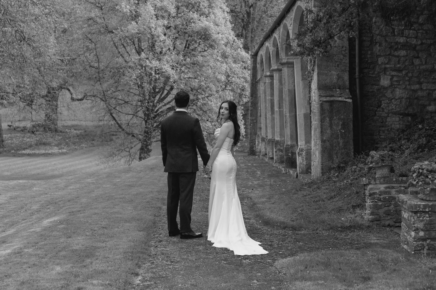 bride and groom walking by some stone arches