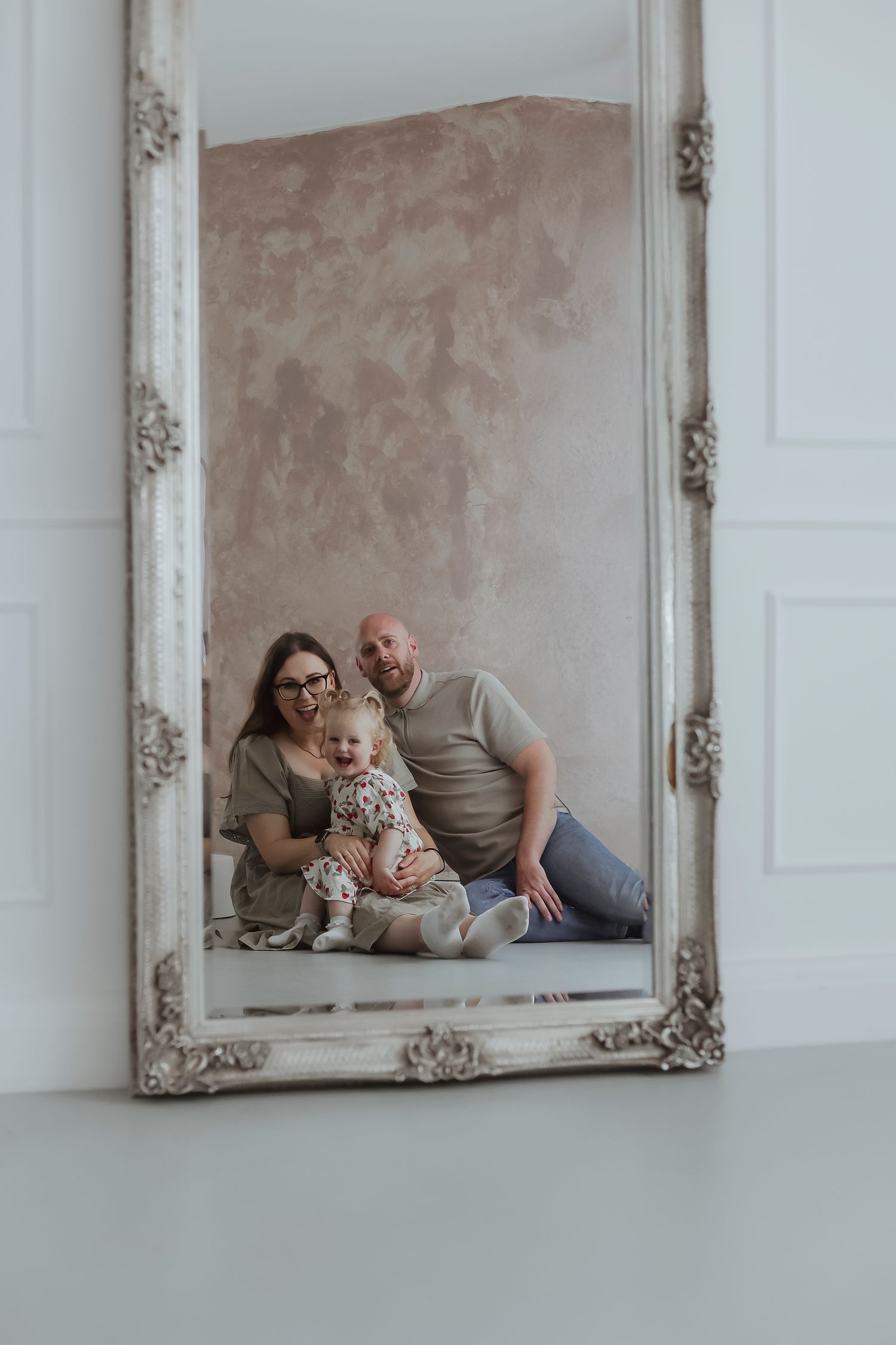 family smiling in the reflection of a mirror