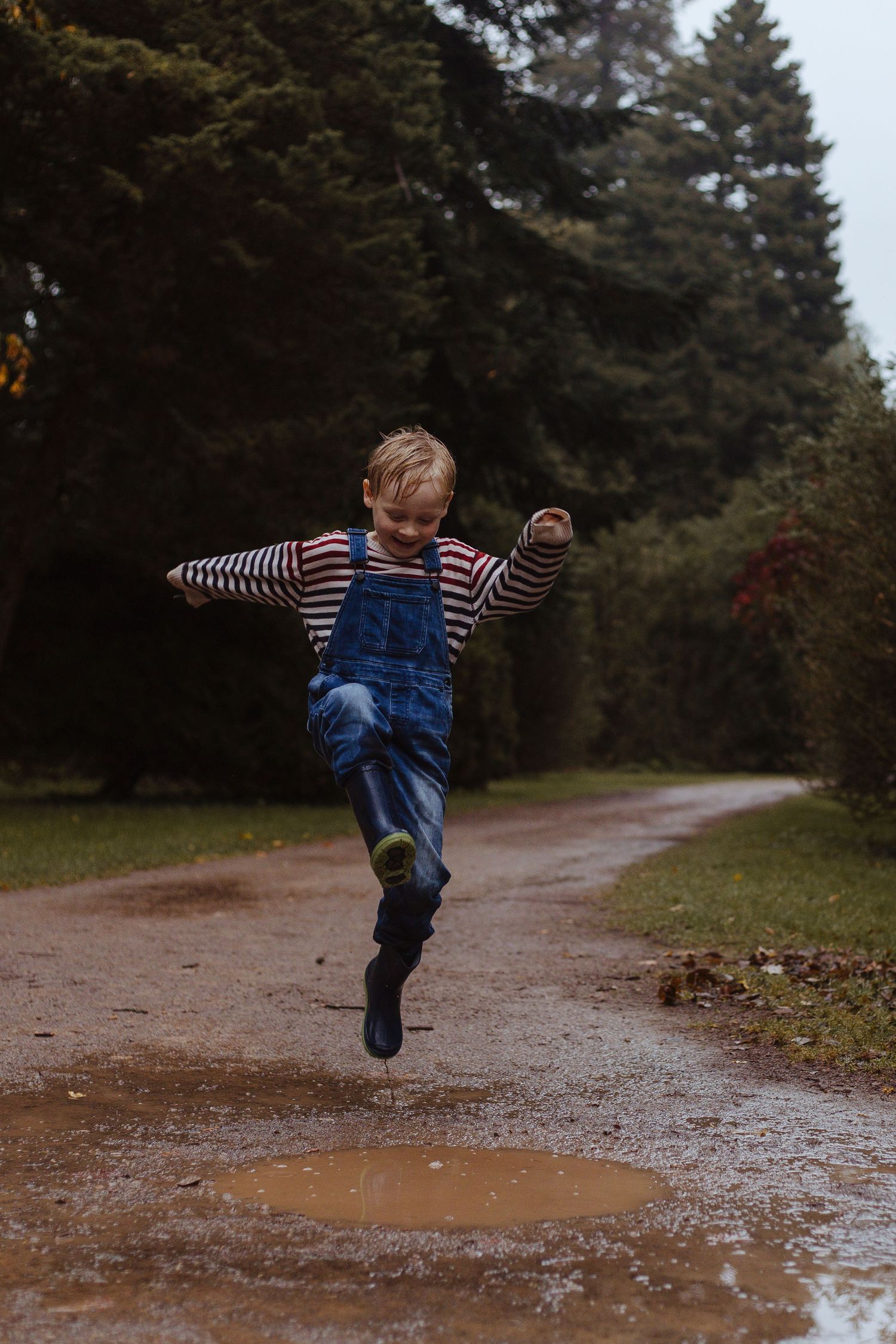 boy jumping in the puddles at westonbirt