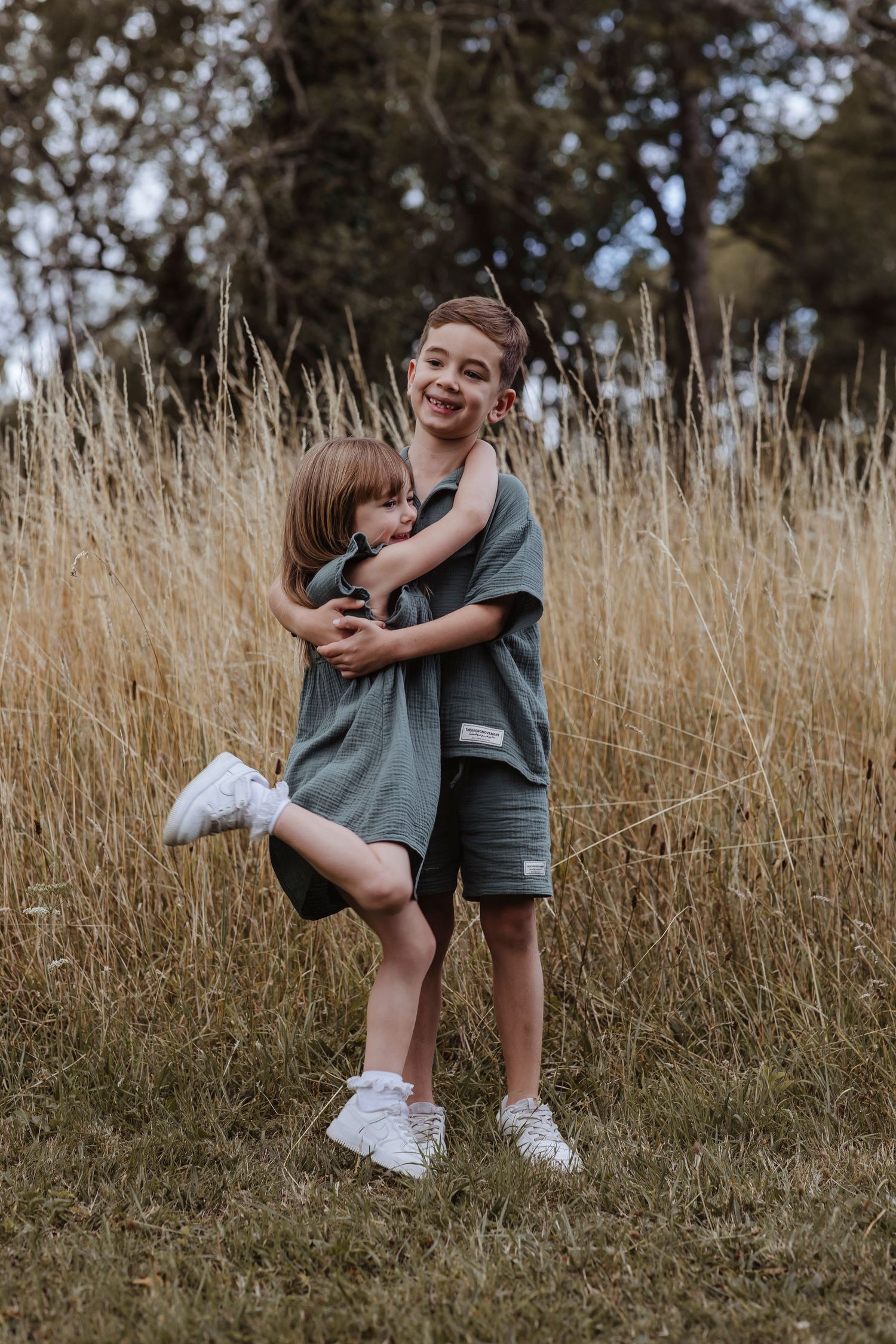 brother and sister hugging in the long grass