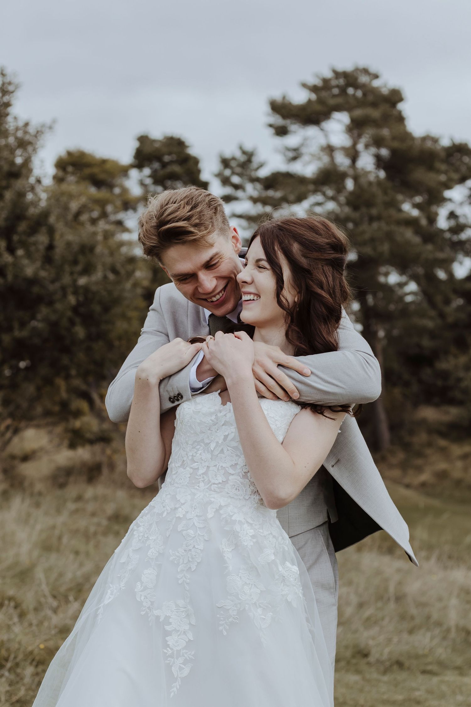 groom embracing his wife as they smile and sway in the countryside