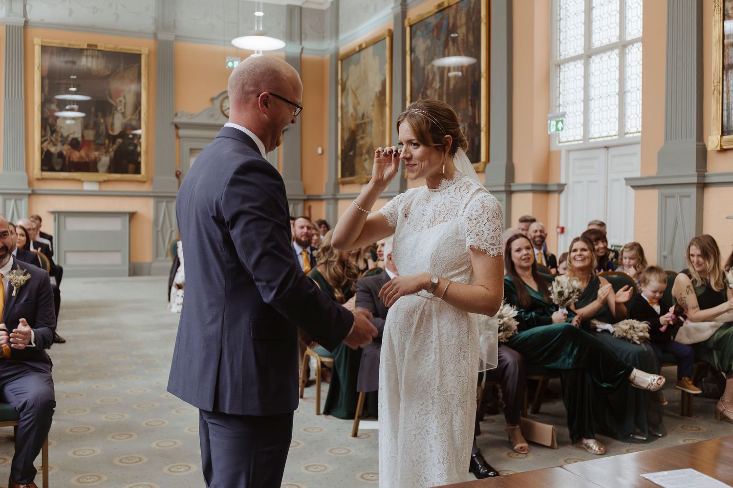 bride crying during ceremony- wiping away her tear