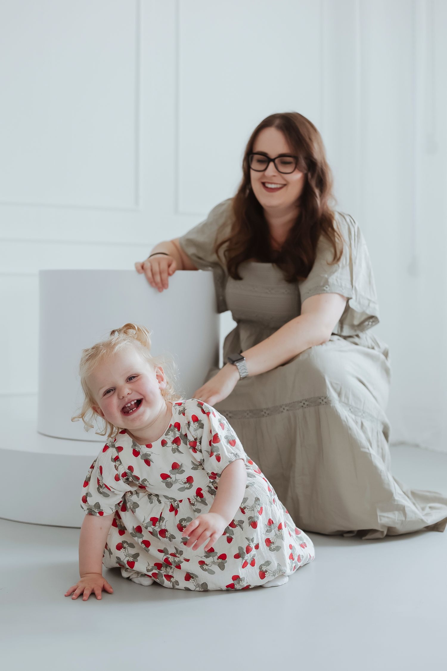 mother and daughter laughing as child crawls away