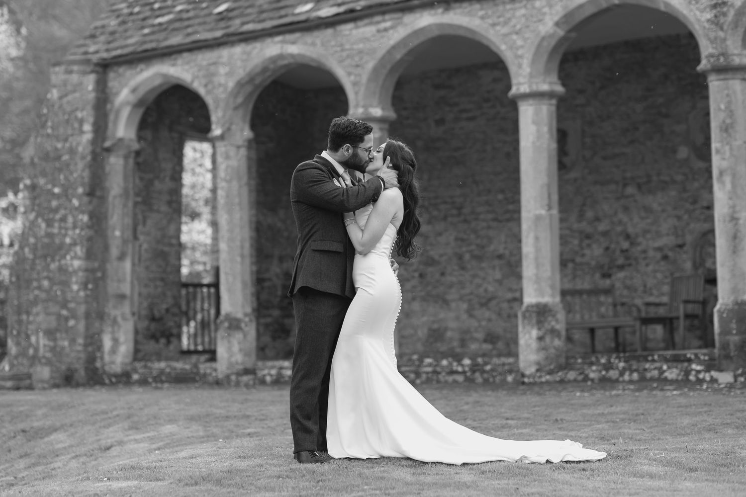 A couple shares a quiet, intimate moment before an old stone archway.
