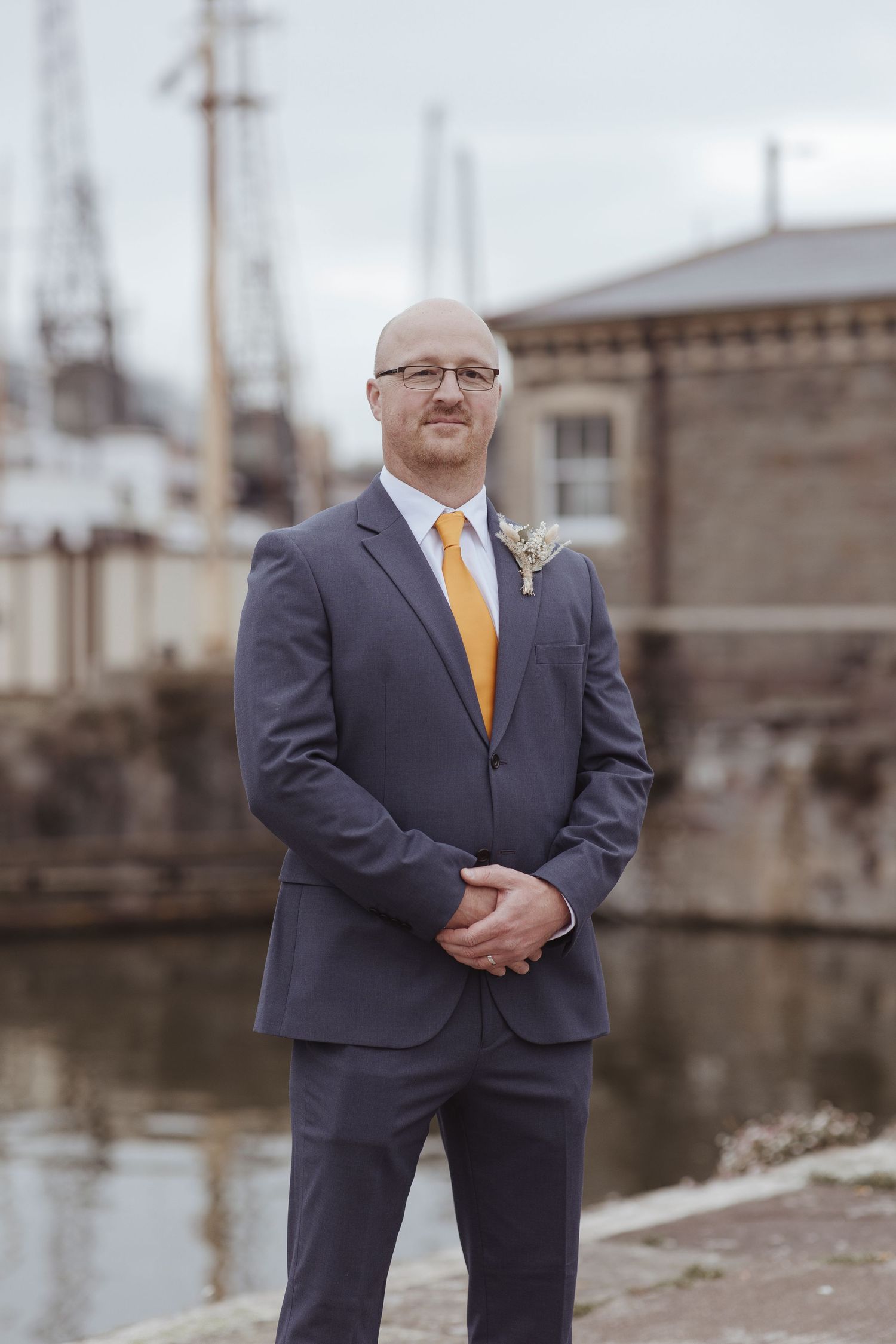 groom portrait - standing inform of water and boats and a stone building