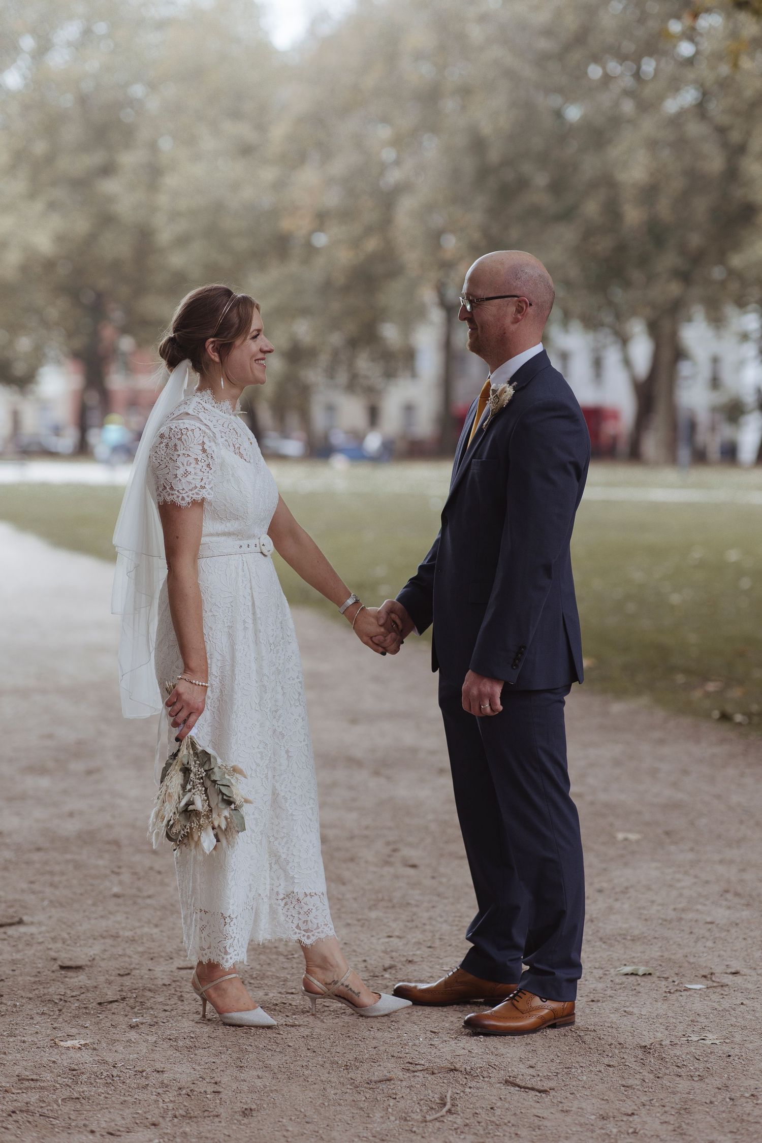 bride and groom holding hands in the park