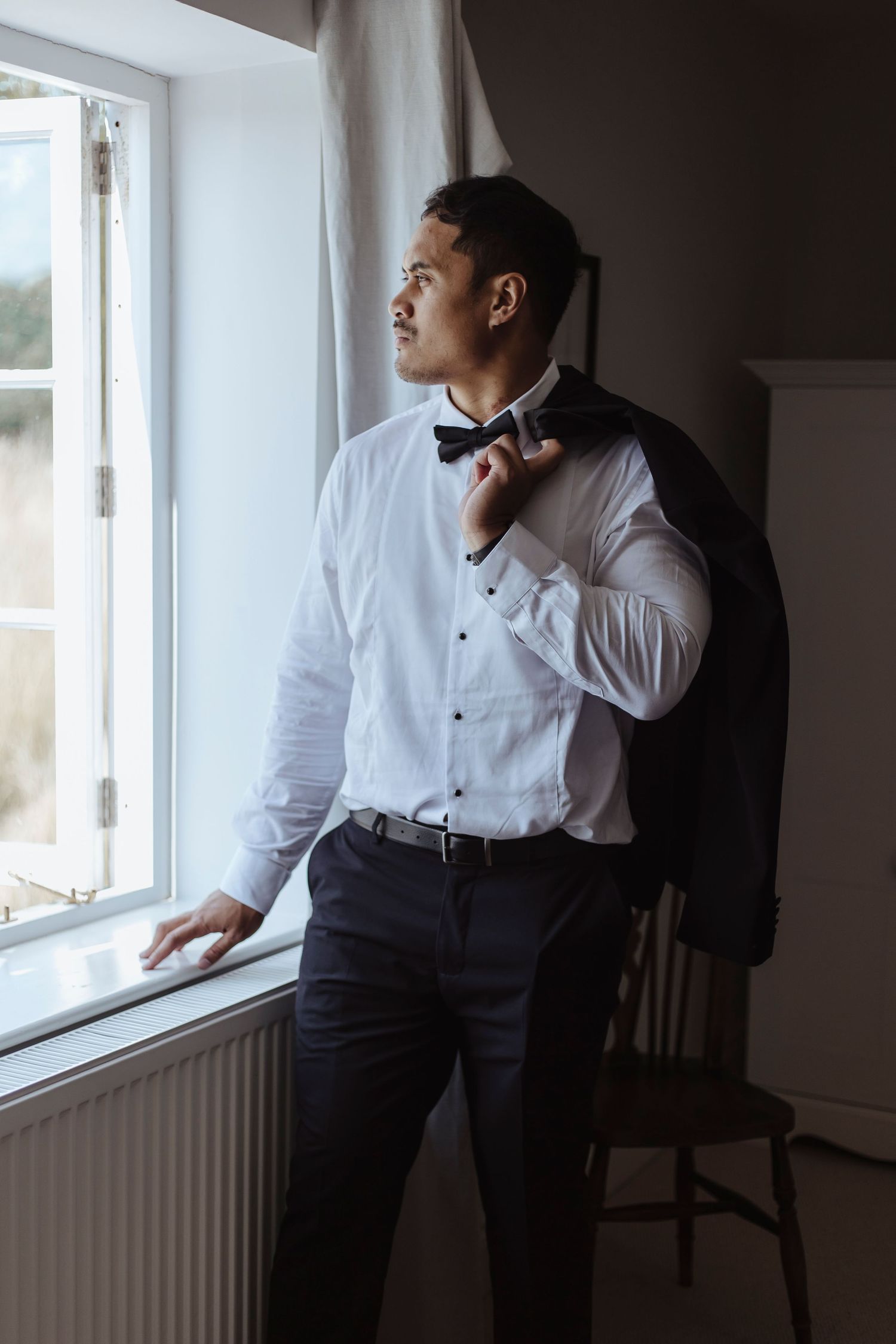 groom holding his jacket staring out the window