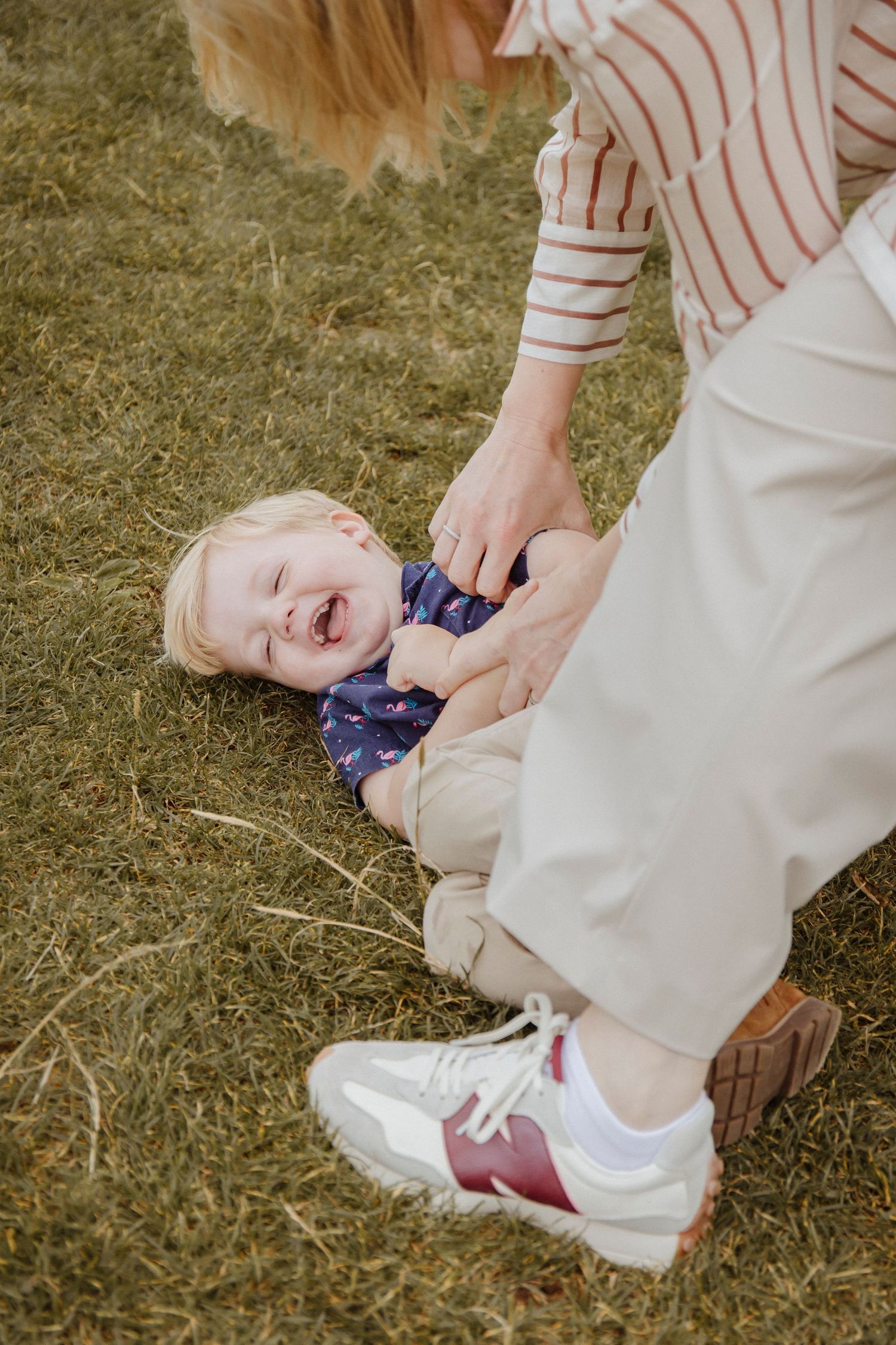 child on the floor laughing whilst being tickled by grandmother