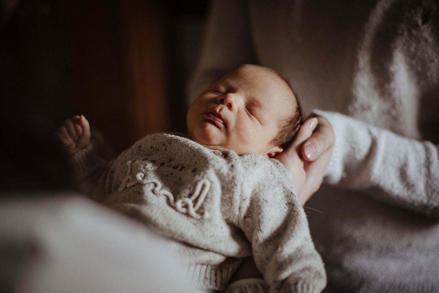 mother and father holding their newborn baby whilst he sleeps