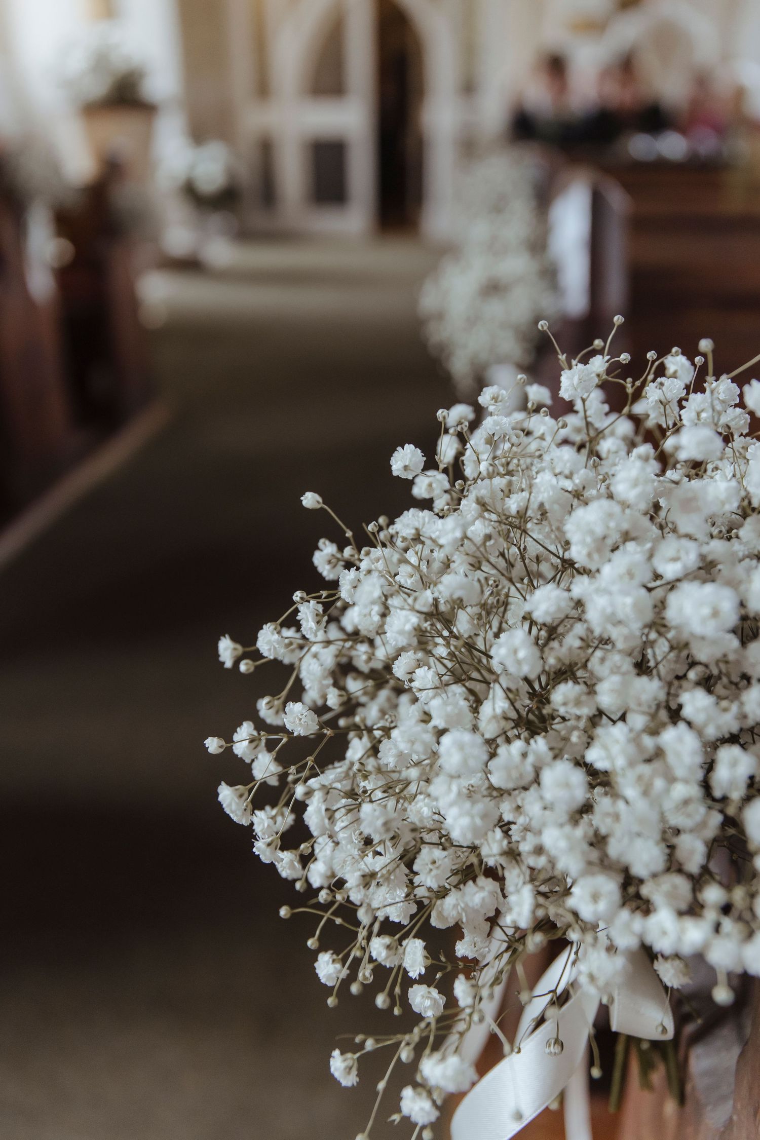 wedding flower decorations pinned to the end of church pews