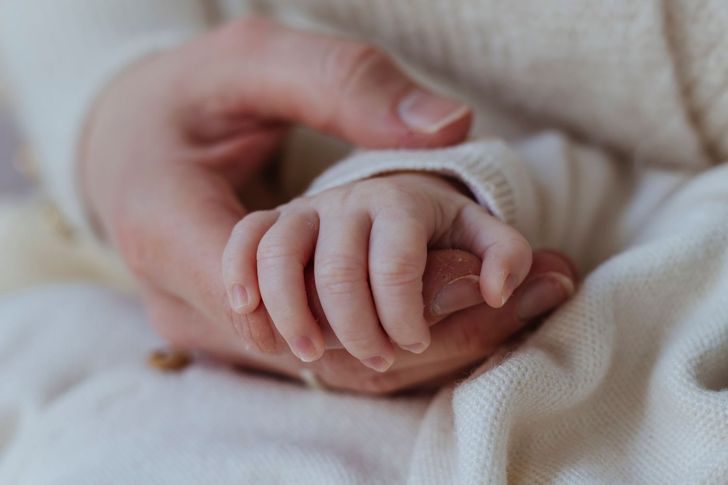 mother holding newborns tiny hand