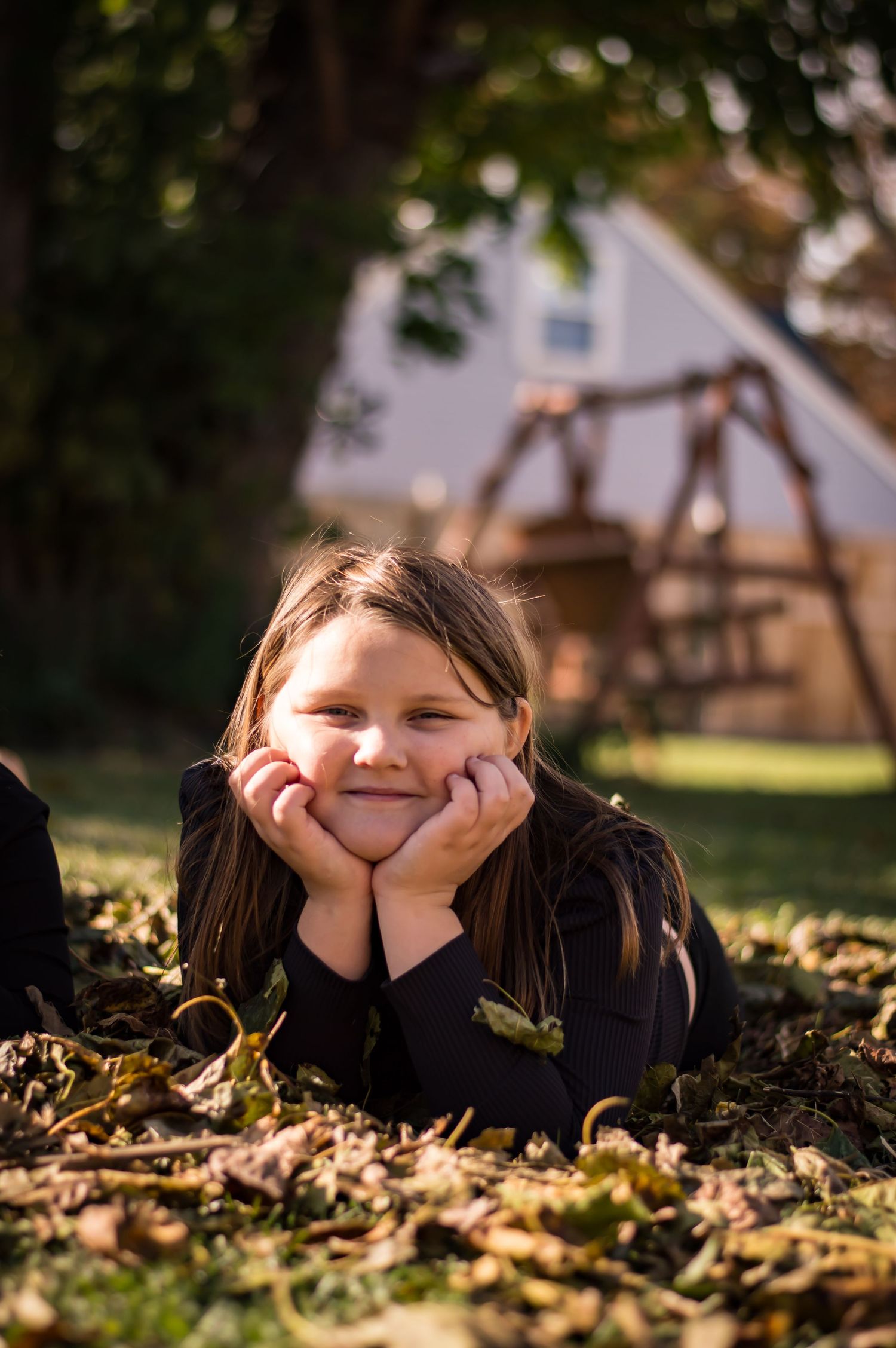 Young person lying in autumn leaves during golden hour photography session.