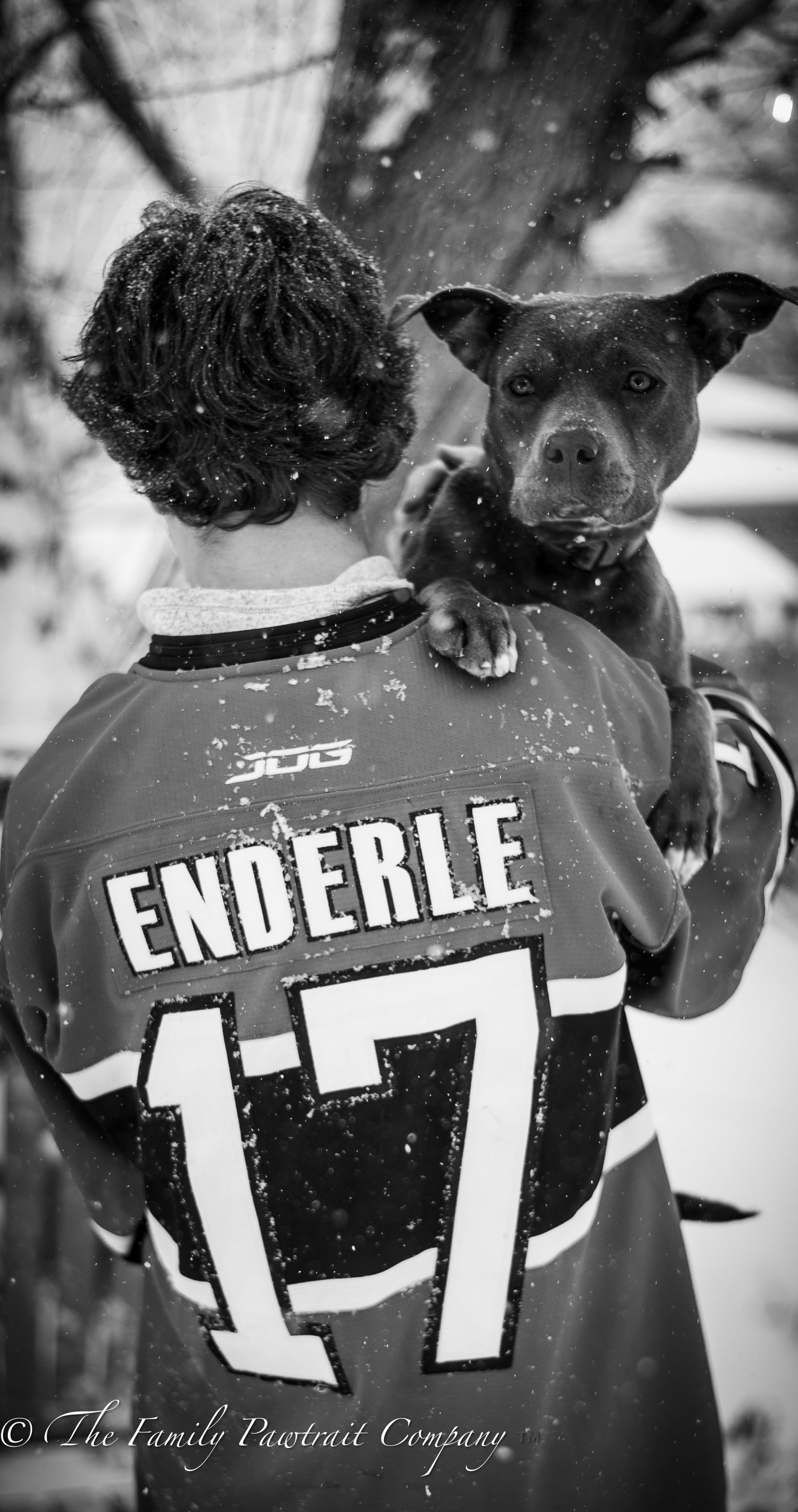 Black and white photo of someone wearing a hockey jersey numbered 17 with 'ENDERLE' on back holding a pit bull dog.