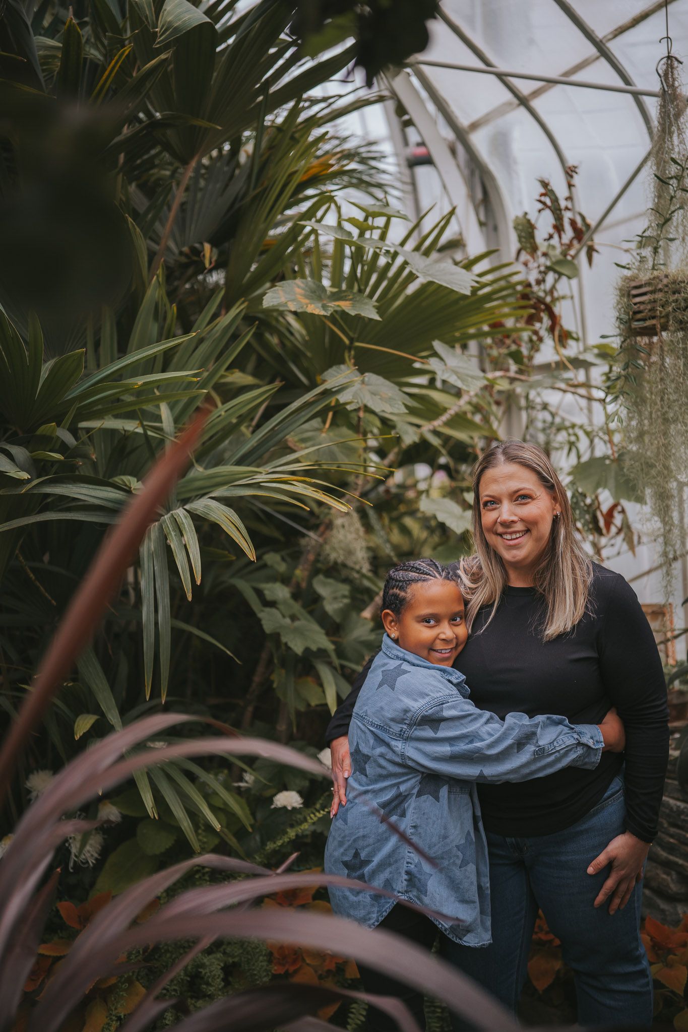 Mother and daughter laughing together inside the Wright Park Botanical Conservatory during a lifestyle family photography session in Tacoma.