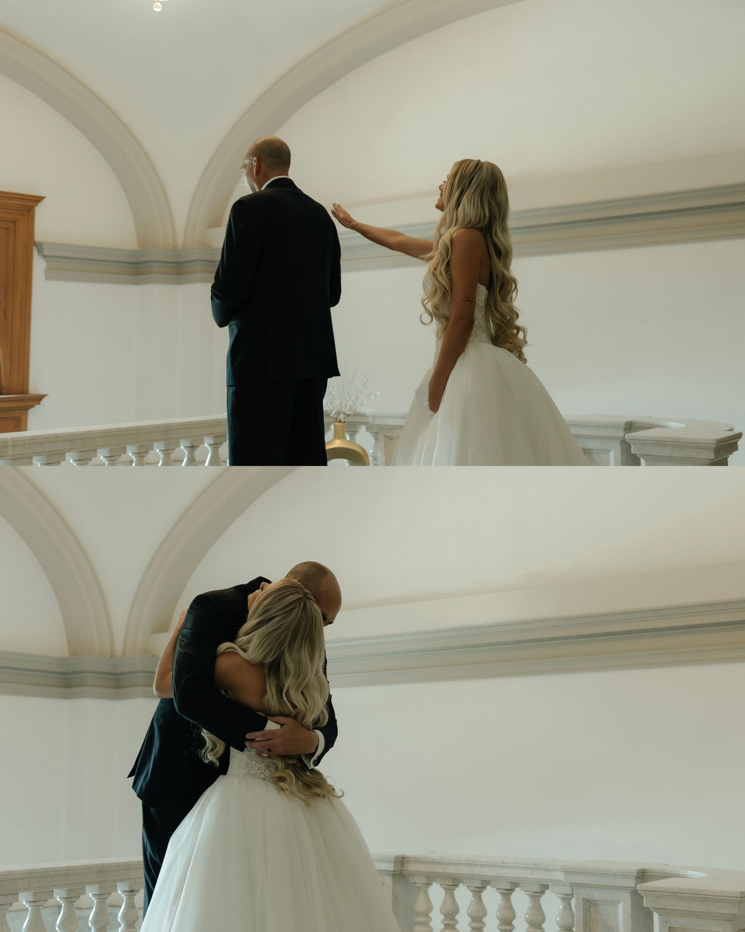 Bride in white gown taps groom's shoulder before emotional first look hug on elegant staircase.