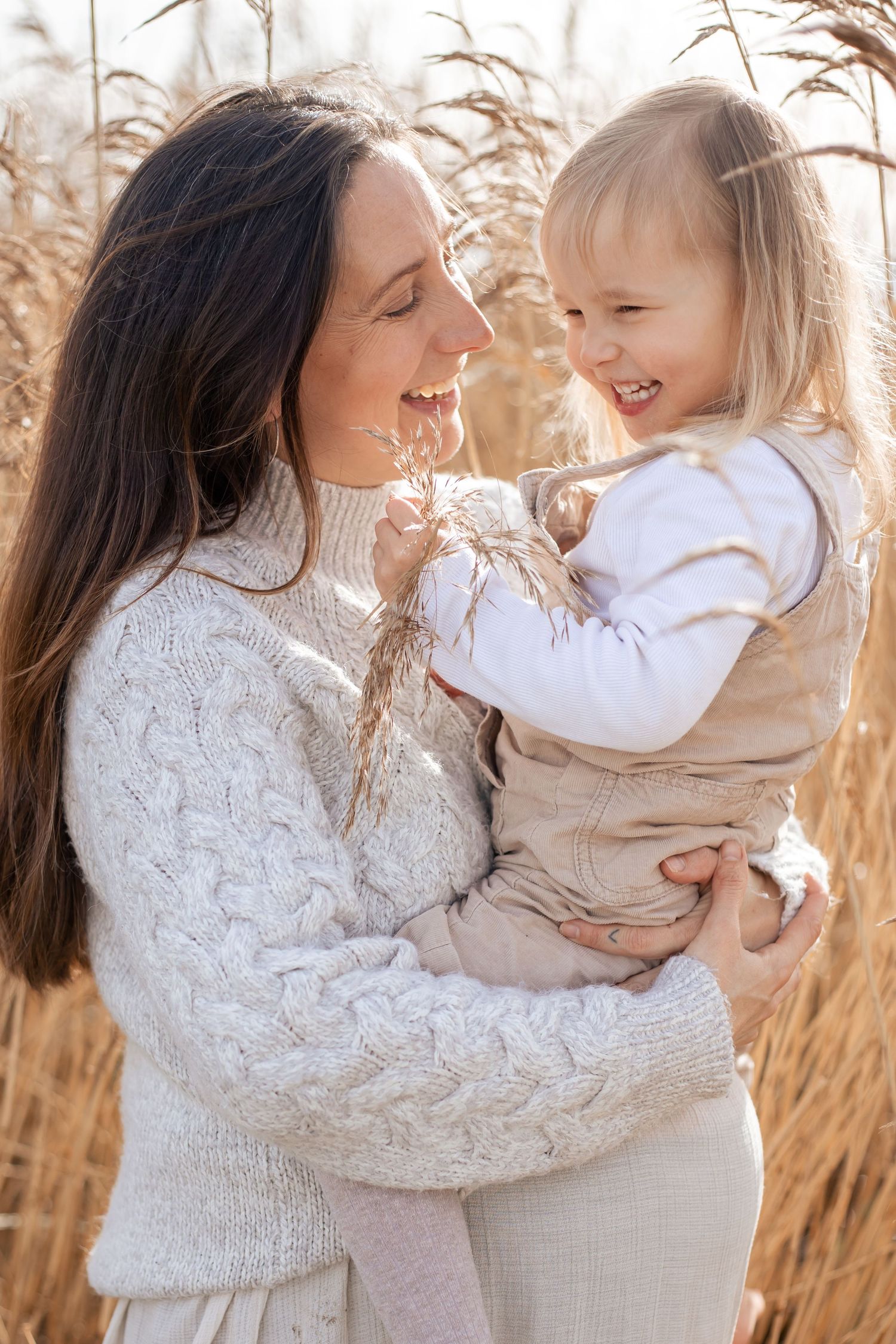 Pregnant mother and young daughter in her arms laughing