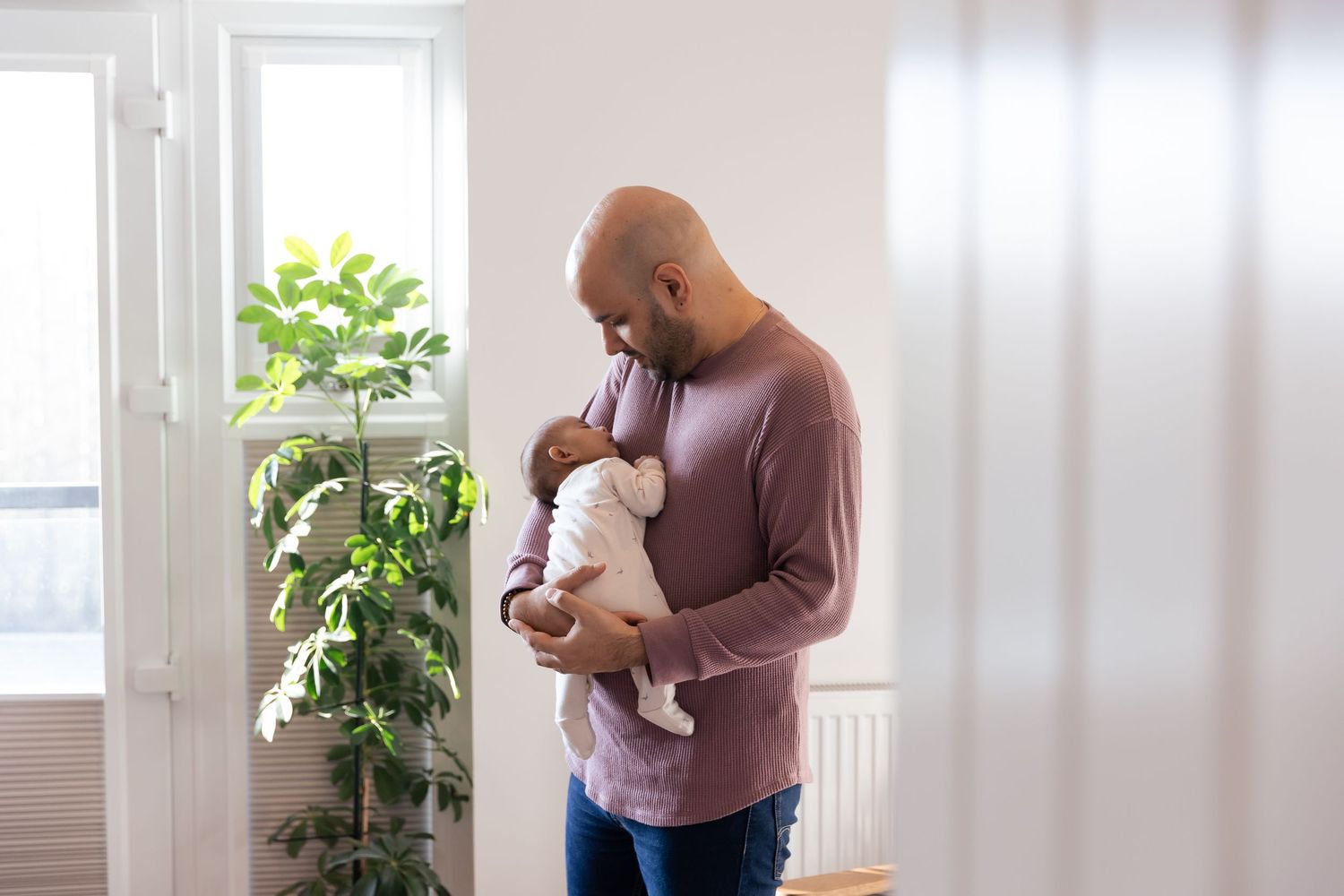 father holding newborn baby daughter in their own home
