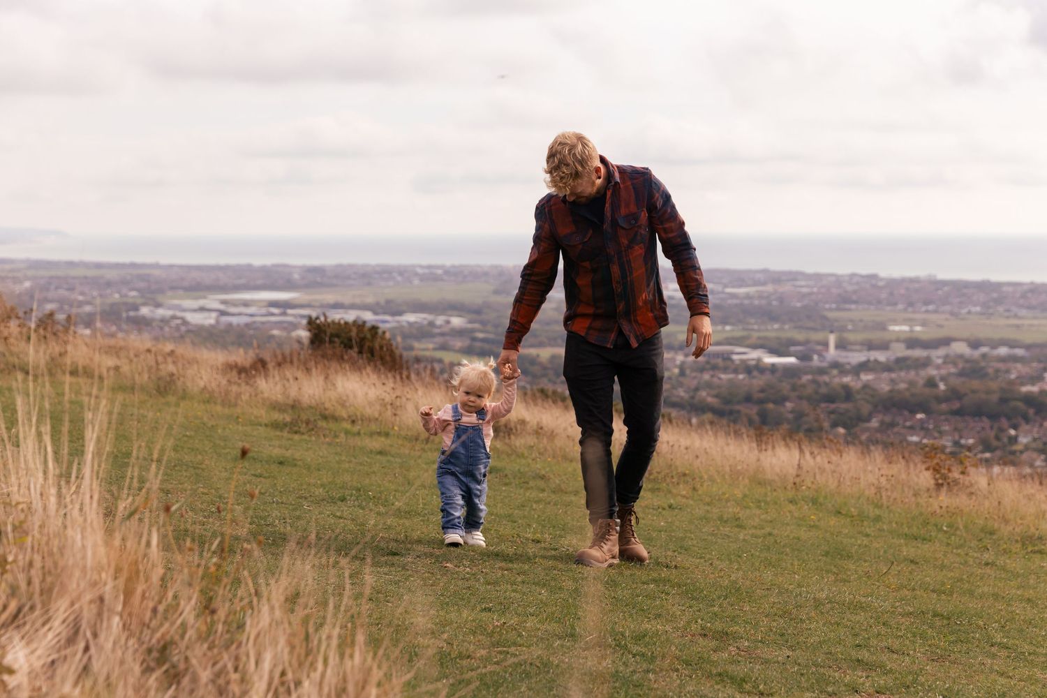 father and young daughter walking hand in hand on the south downs
