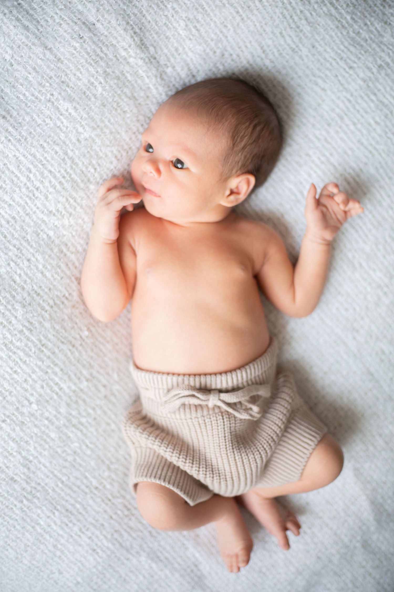 newborn baby boy lying with eyes open on a blanket