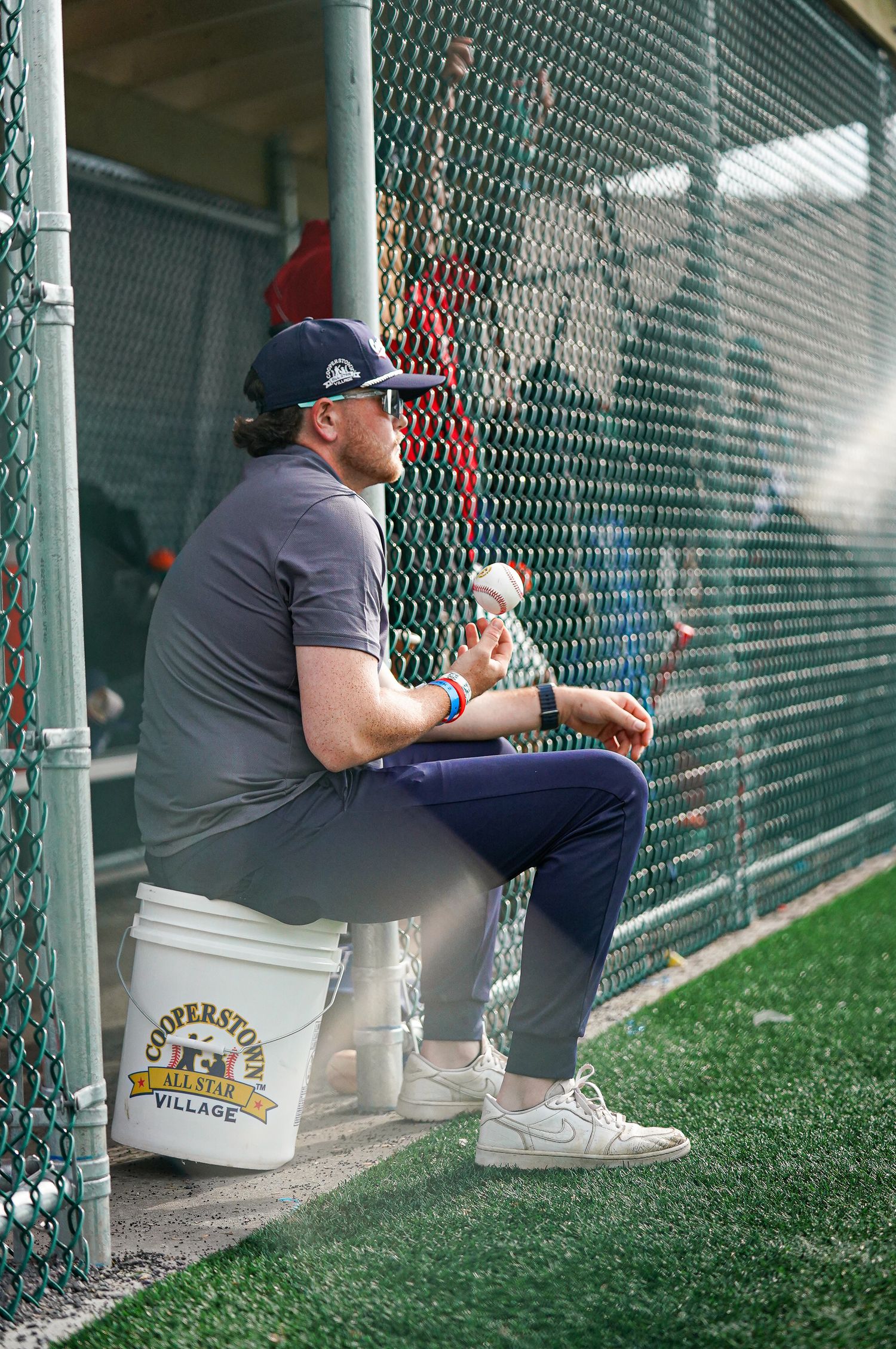 Baseball coaches and staff sitting in dugout during game.