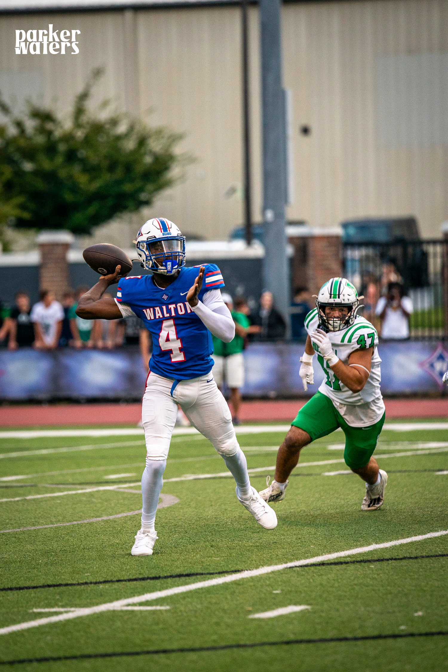 Football players in blue and green uniforms engage in dynamic gameplay action.