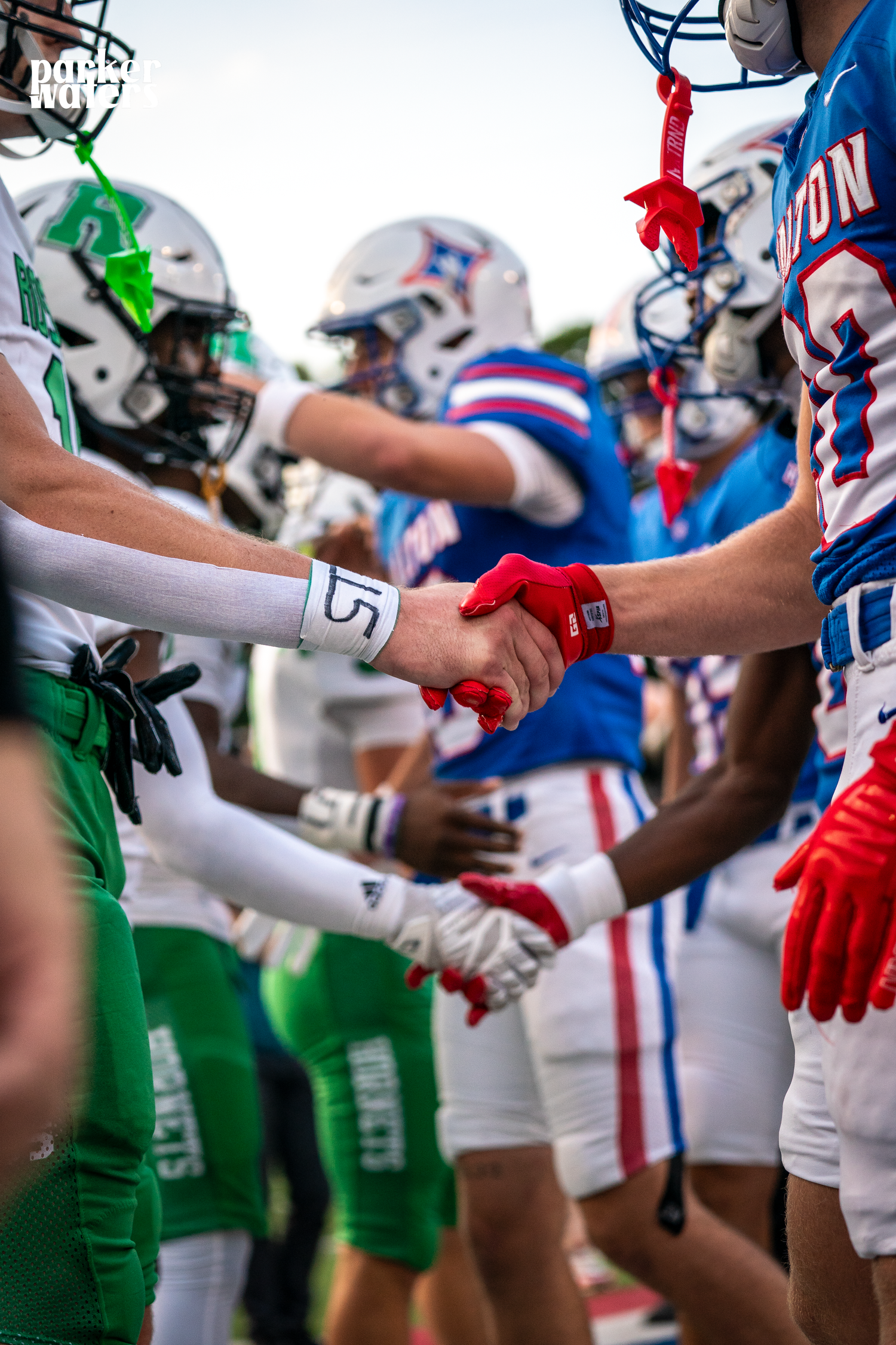 Football players from opposing teams shake hands in a display of sportsmanship.