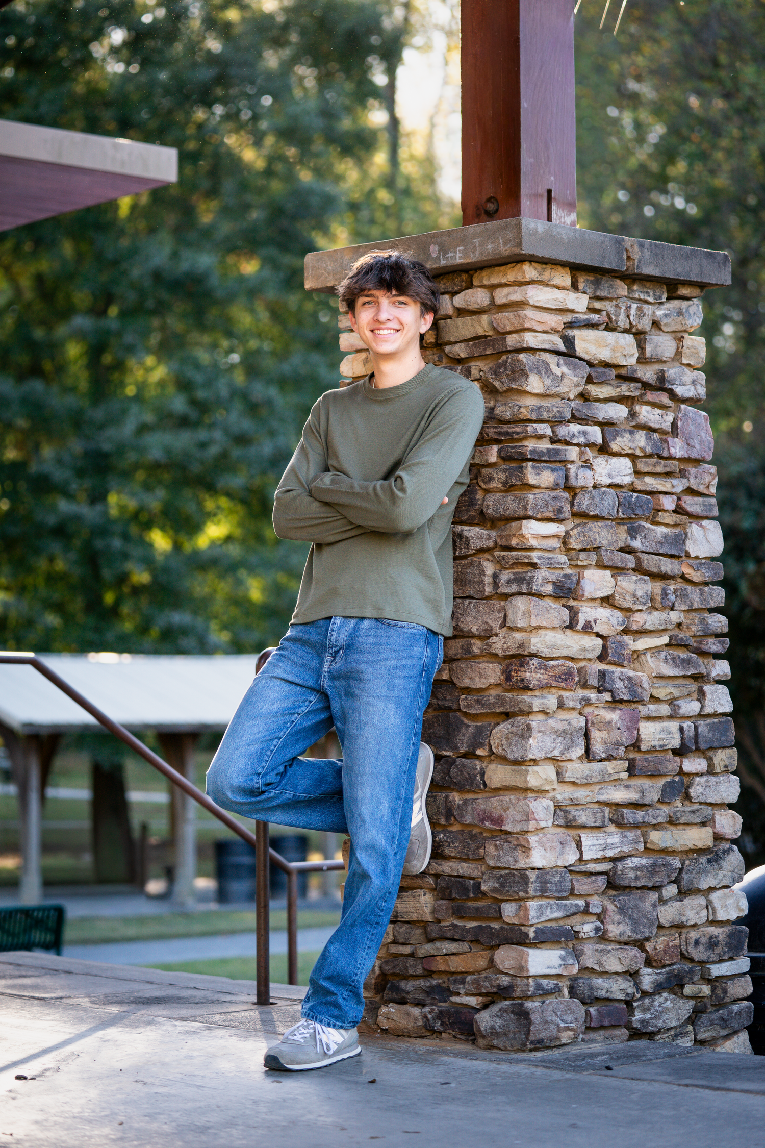 Casual portrait series against a stone pillar wearing jeans and olive green top.