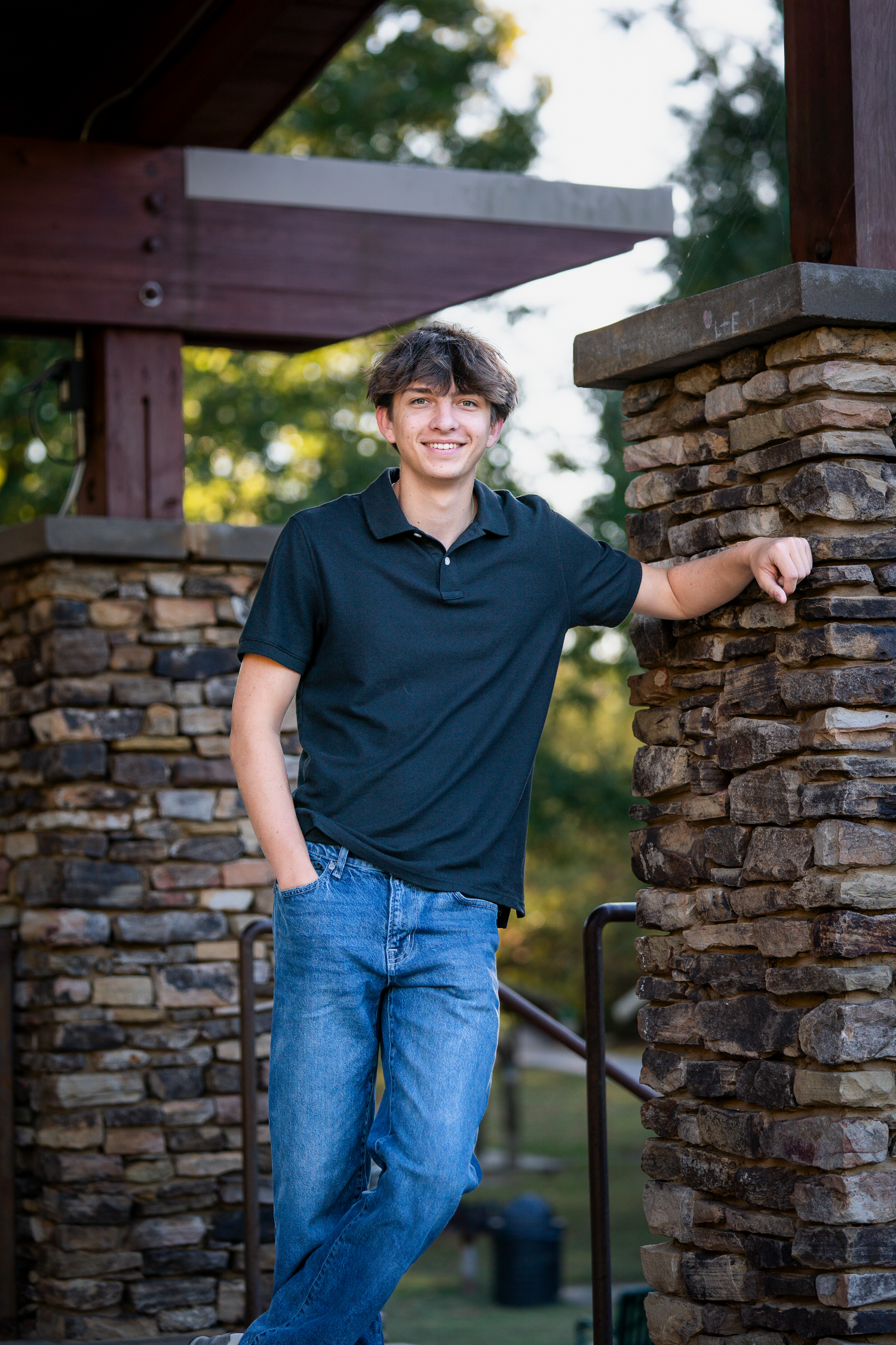 Casual portrait against a rustic stone wall and wooden beams in natural lighting.