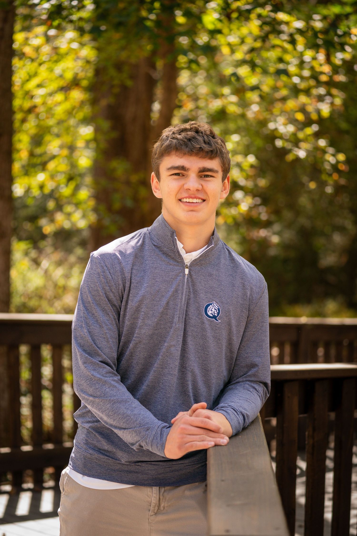 Casual portrait on wooden deck with autumn foliage in background.