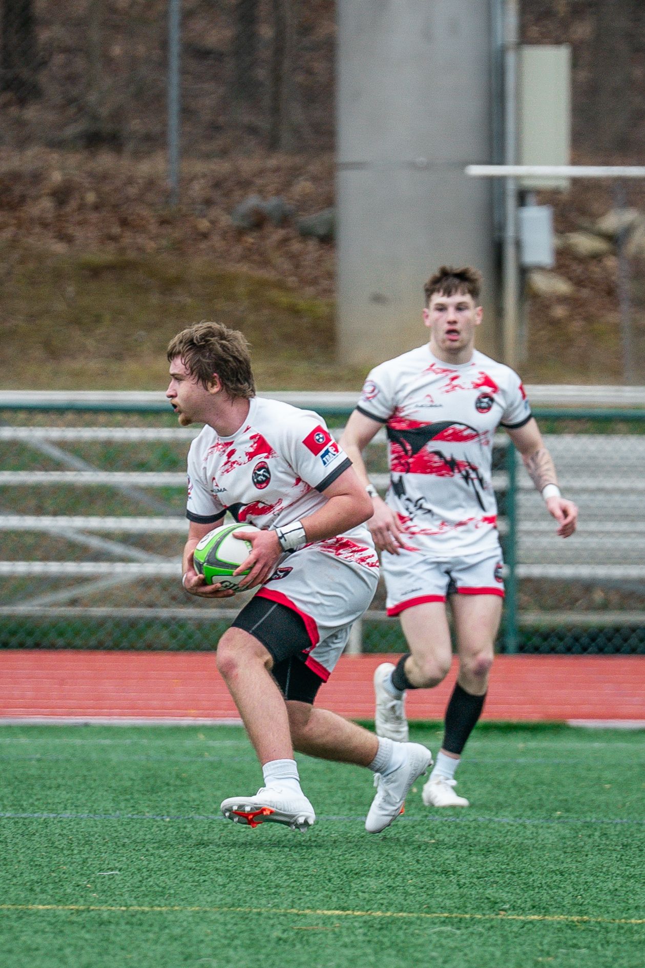 Rugby player dives to score a try on artificial turf field during competitive match.
