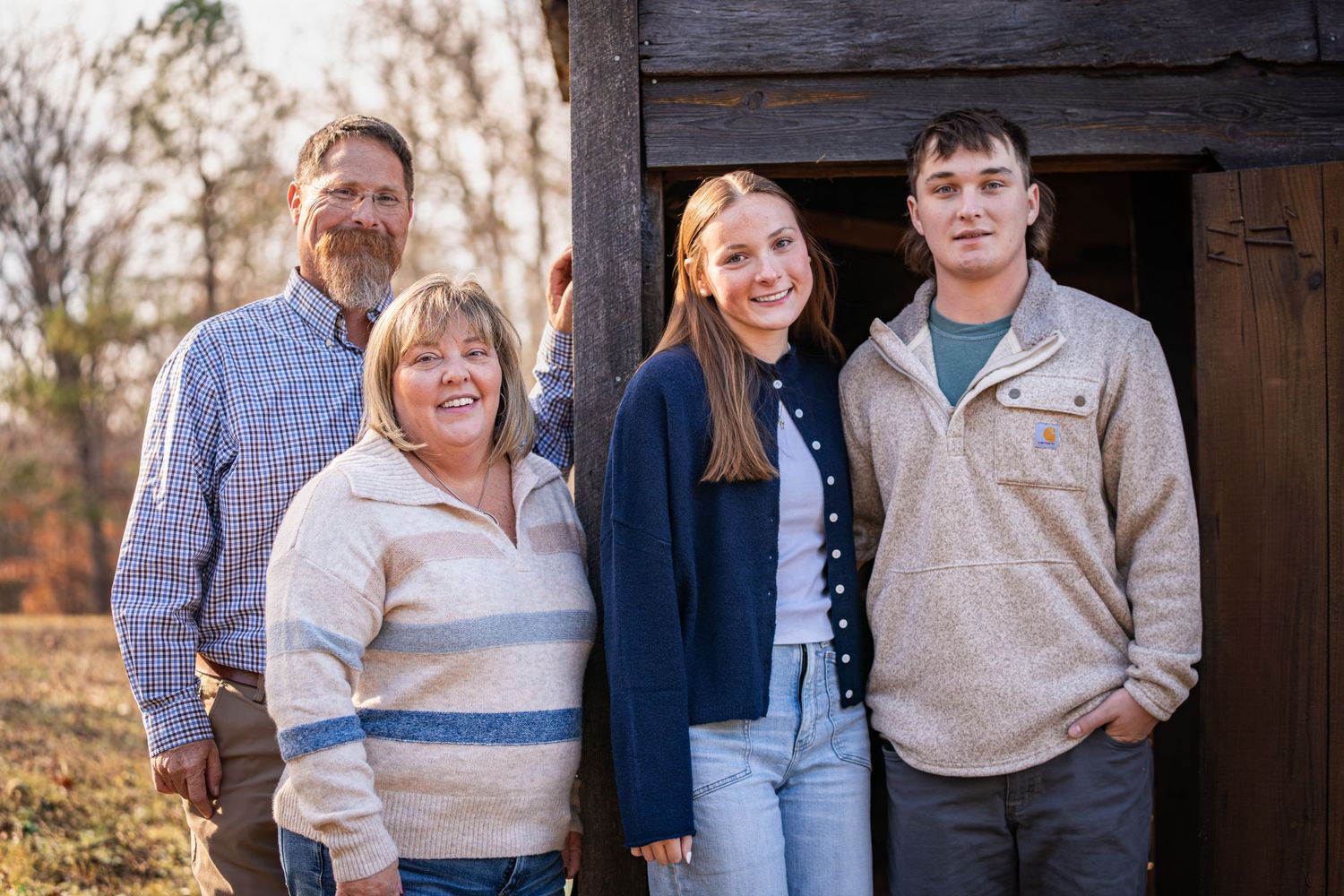 A group poses together outdoors in coordinated beige and blue casual outfits during an autumn photo session.
