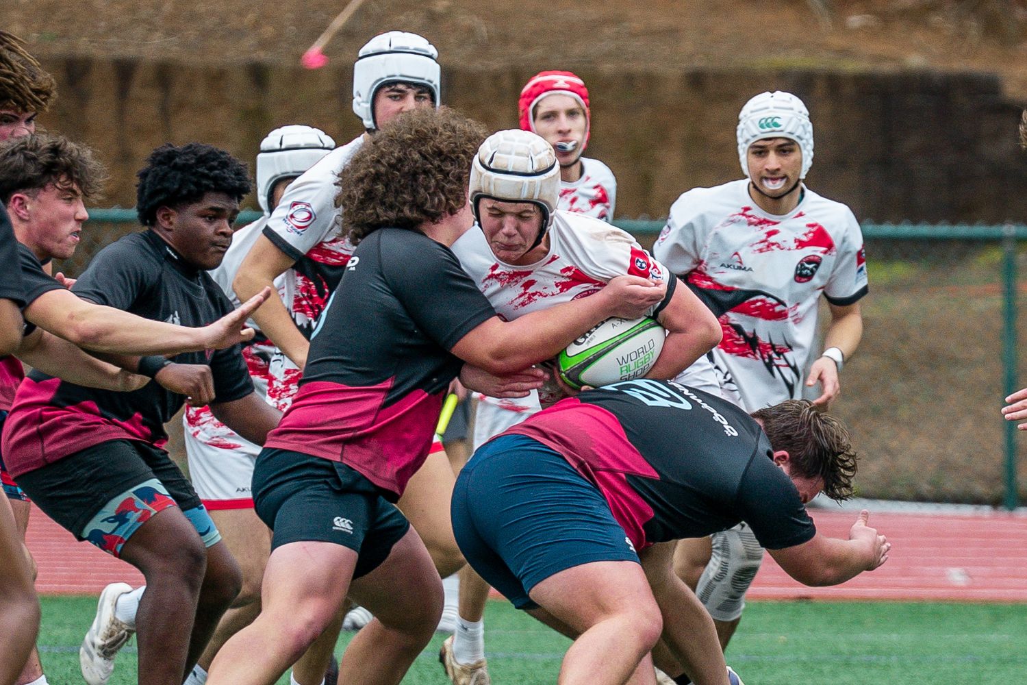 Rugby players engage in an intense tackle during a competitive match on an outdoor field.