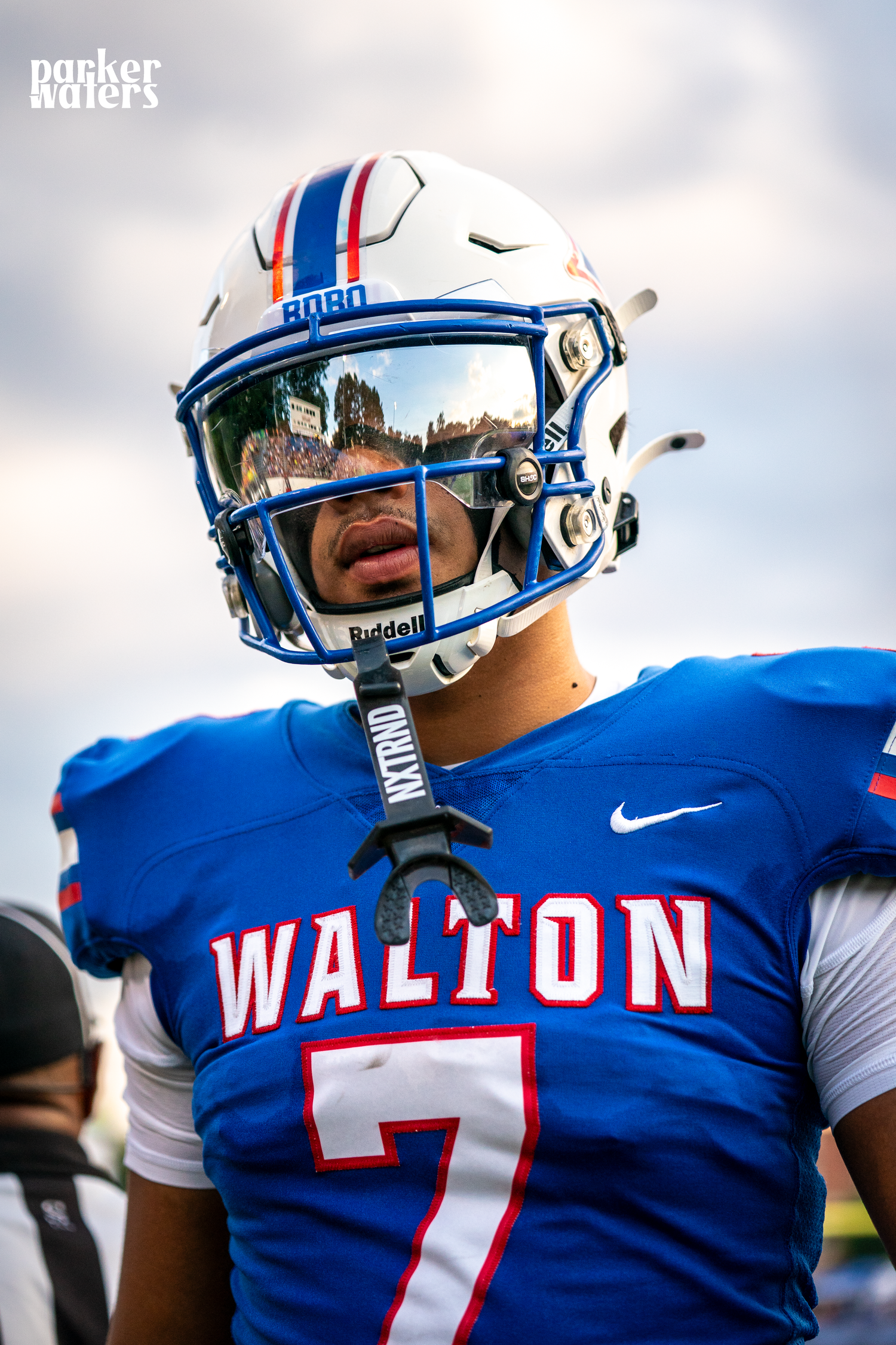 Football player in blue uniform with number 7 jersey and reflective visor helmet.