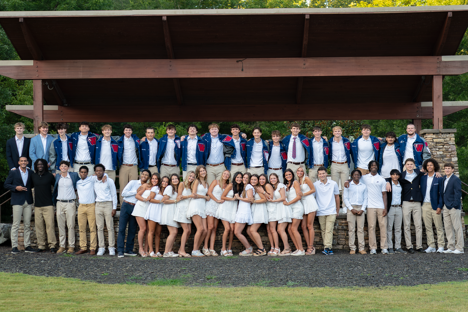 Students in matching white and khaki outfits posed together outdoors.