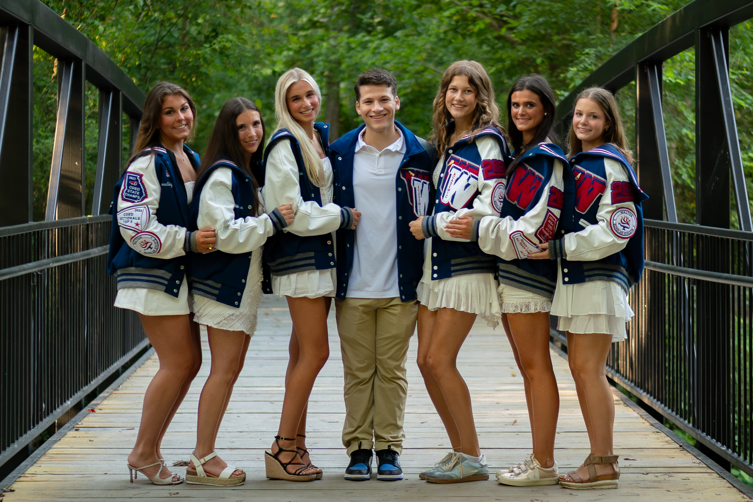 Large group photo of students lined up on a wooden bridge in coordinated outfits.