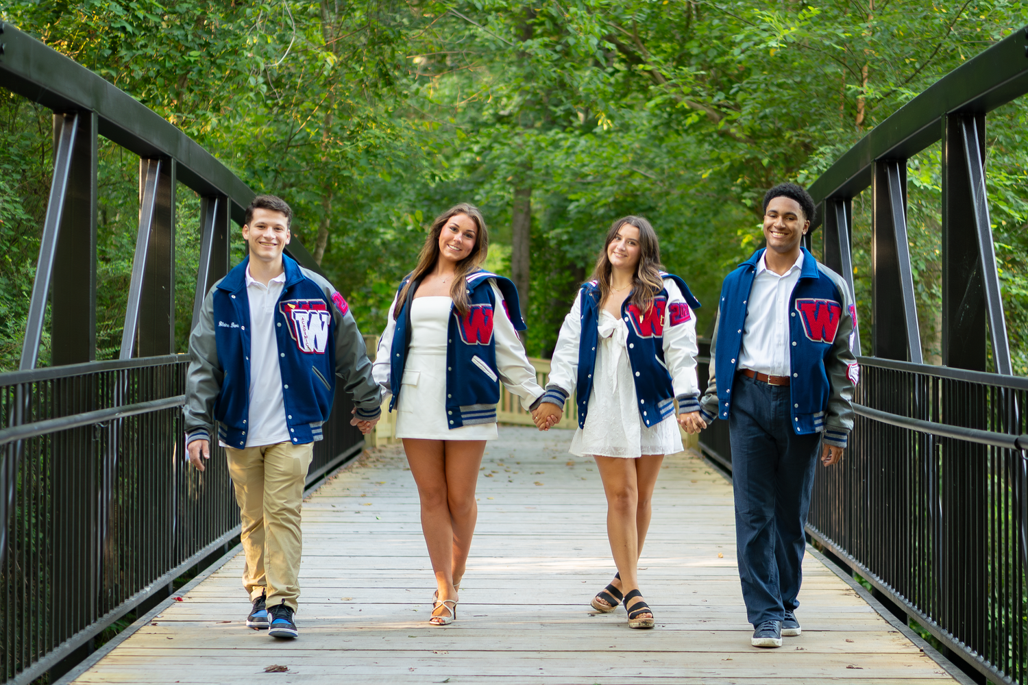 Group walking together on a metal bridge surrounded by lush green foliage.